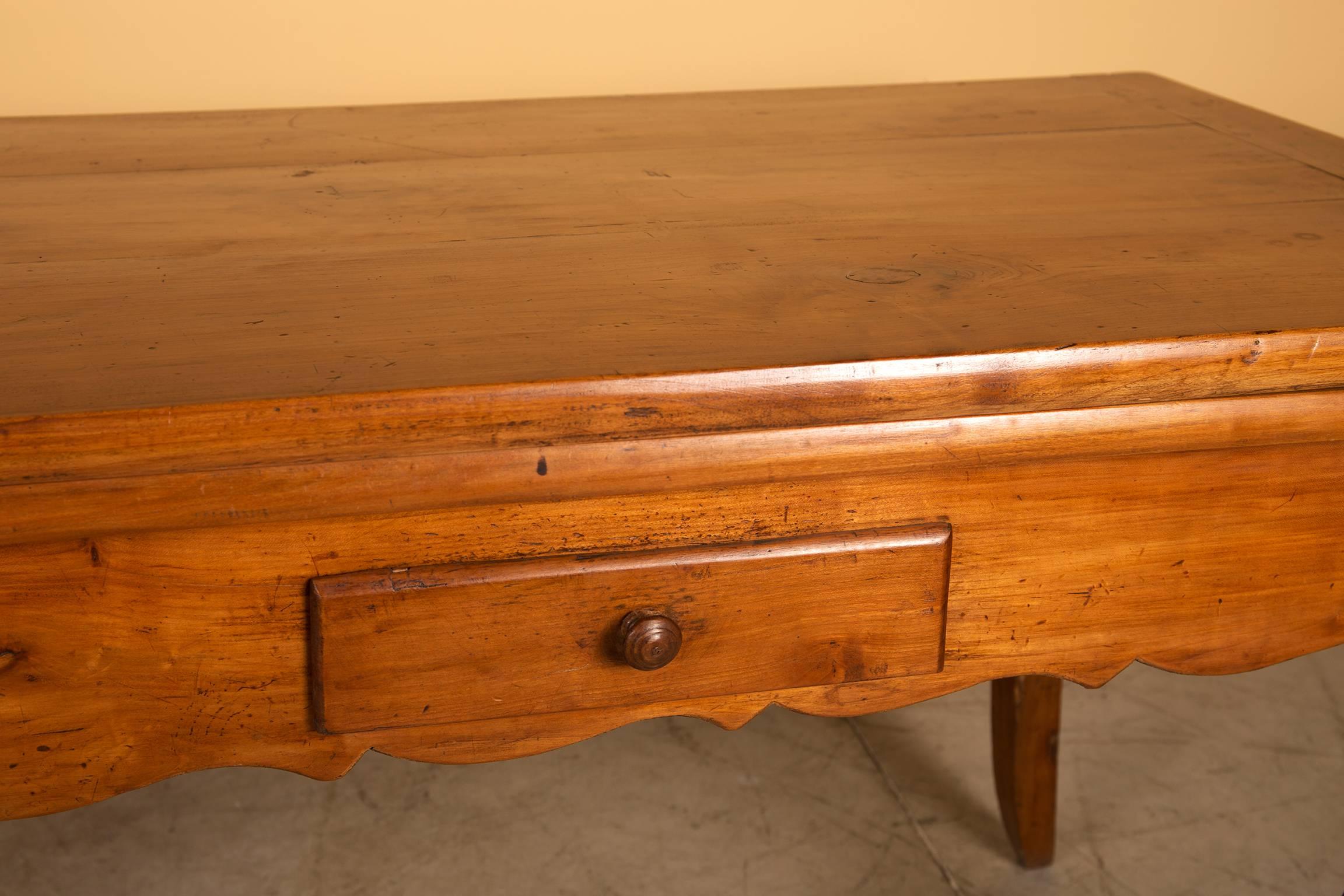 French Provincial farm table in nice and untouched condition. In the Louis XV style with cabriole legs and a scalloped apron. The table has two drawers, on each side one. 
This table is made in cherrywood and has the original extendable leaves on