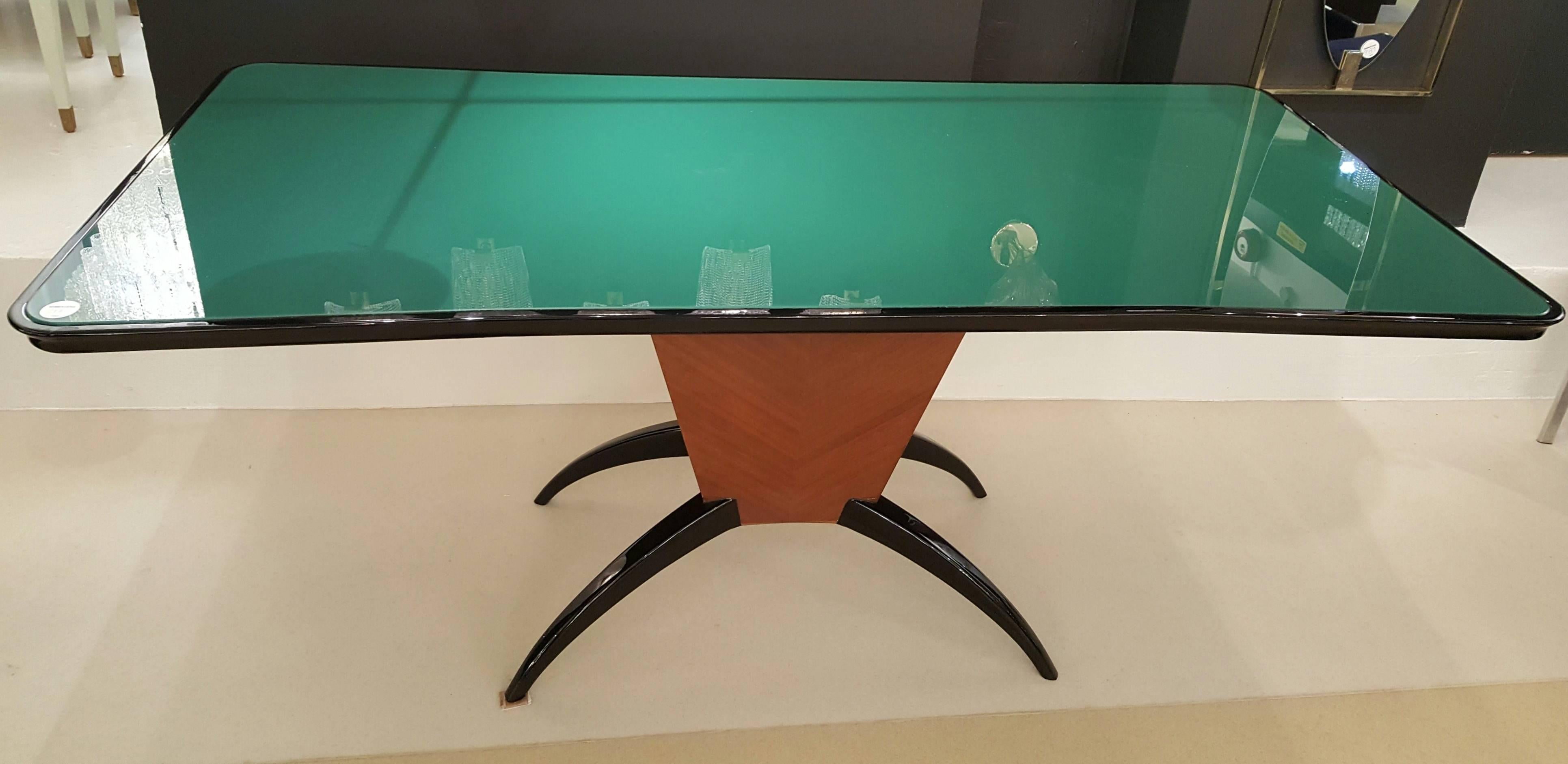 A Mid-Century Italian dining table or desk in rosewood with black lacquered spider legs and green glass top.