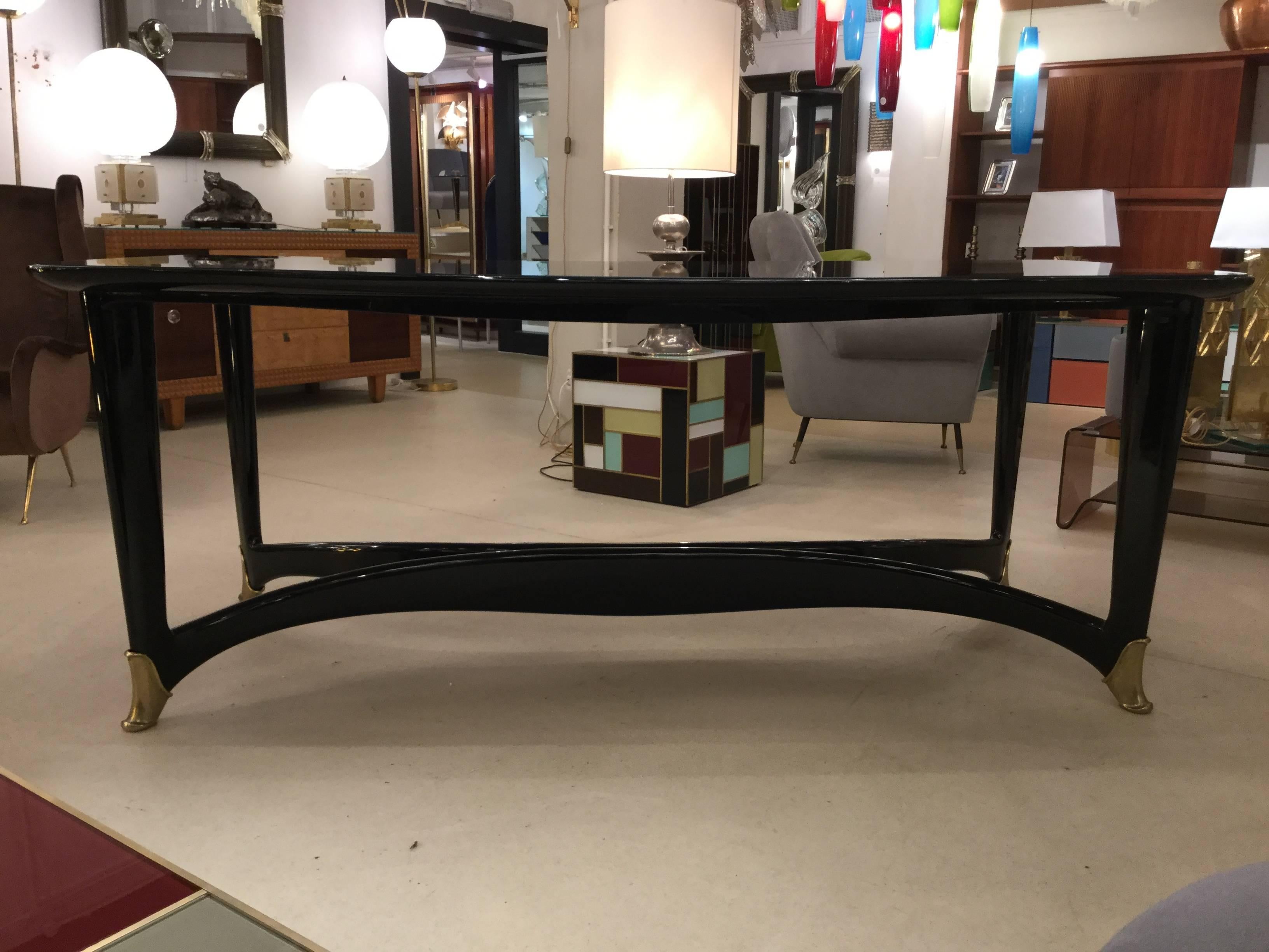 An Italian designed dining table / or could work as a great desk ebonized wood with glass top sculptural legs leading to brass shoes by  to Paolo Buffa for Dassi