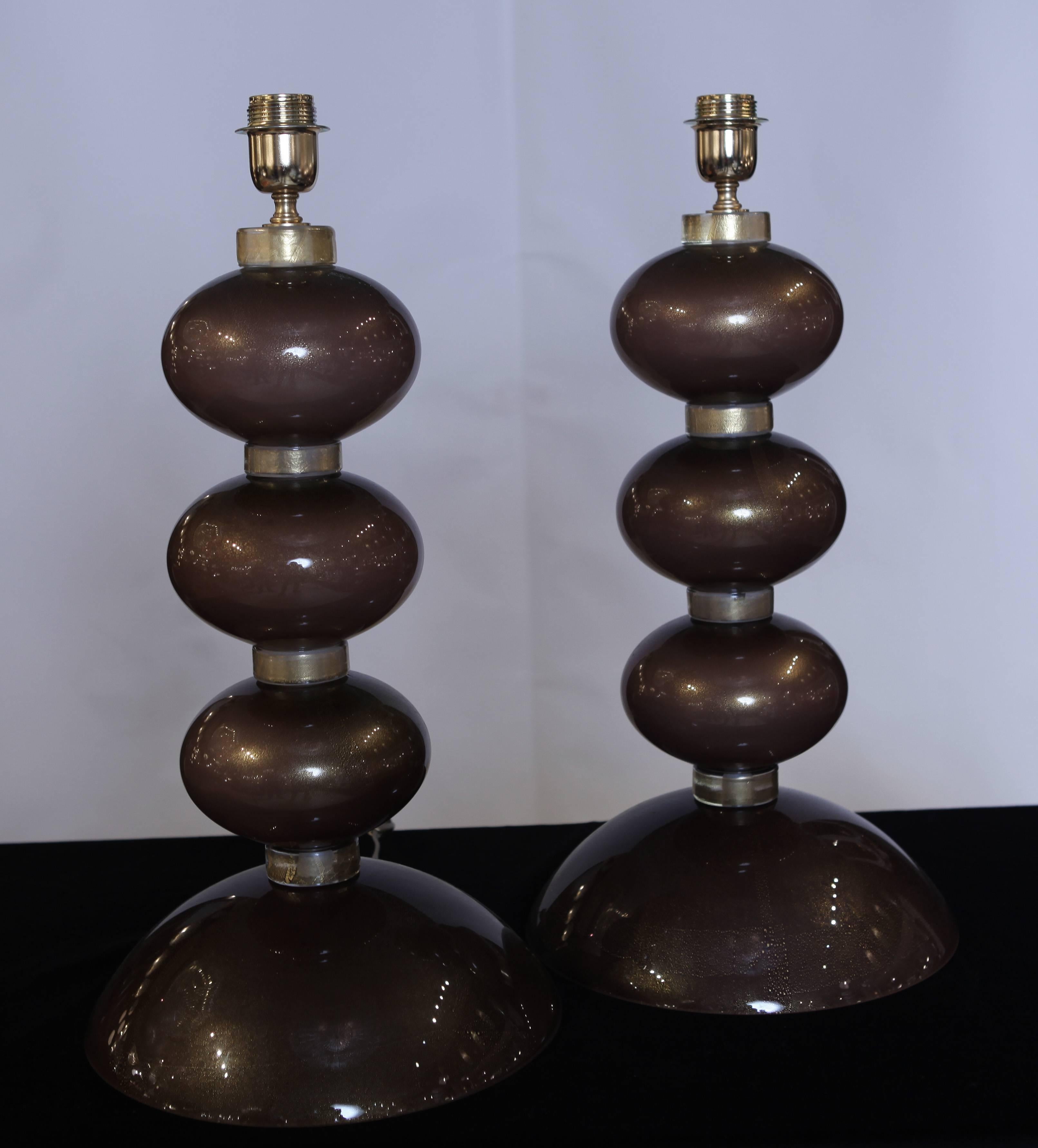 The table lamps are made up of three oval bronzed Murano glass pieces sitting on a large base. The components are fused to Murano glass discs with gold inclusion.
   