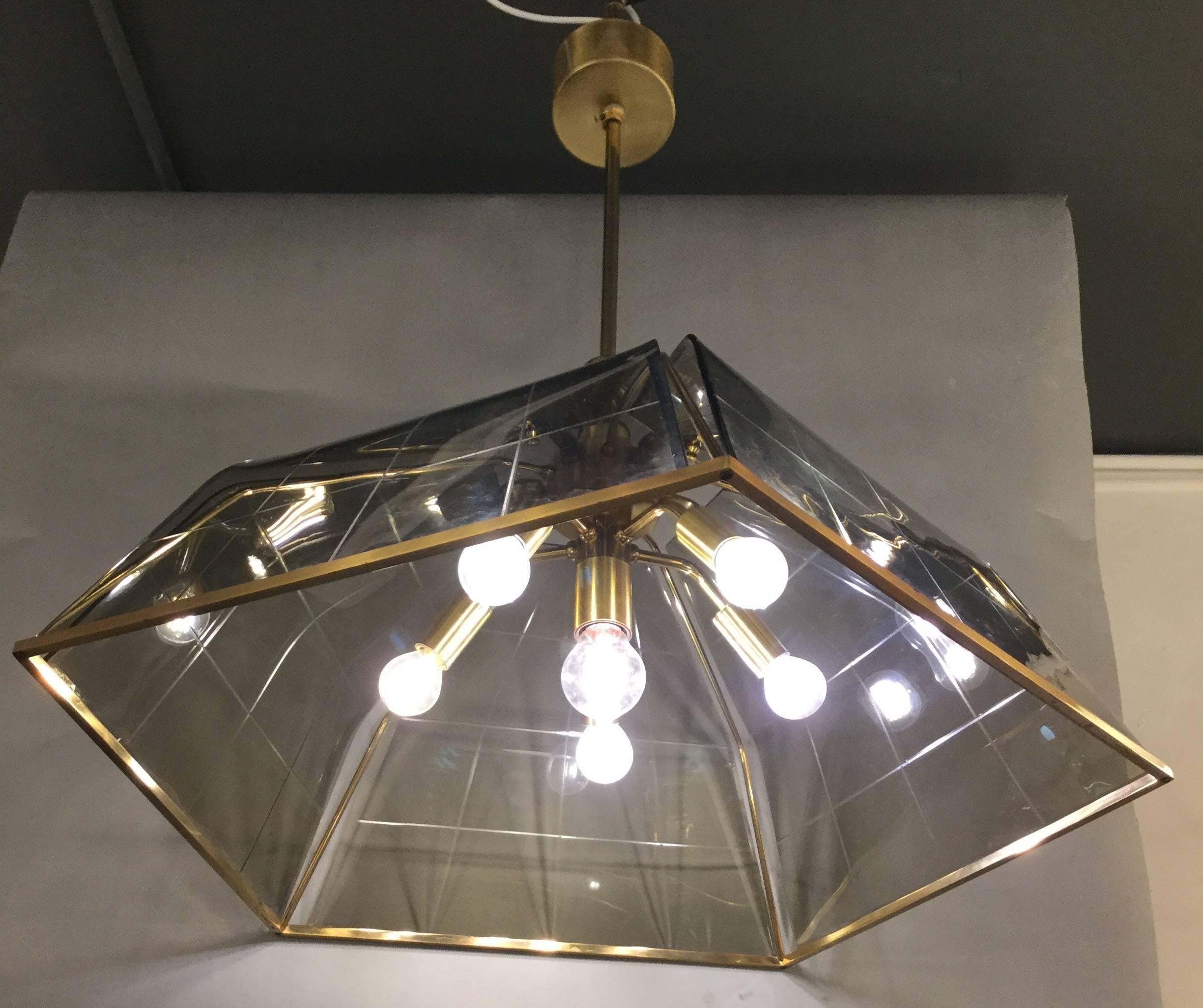 A pentagonal ceiling lamp in grey glass mounted on a brass frame.