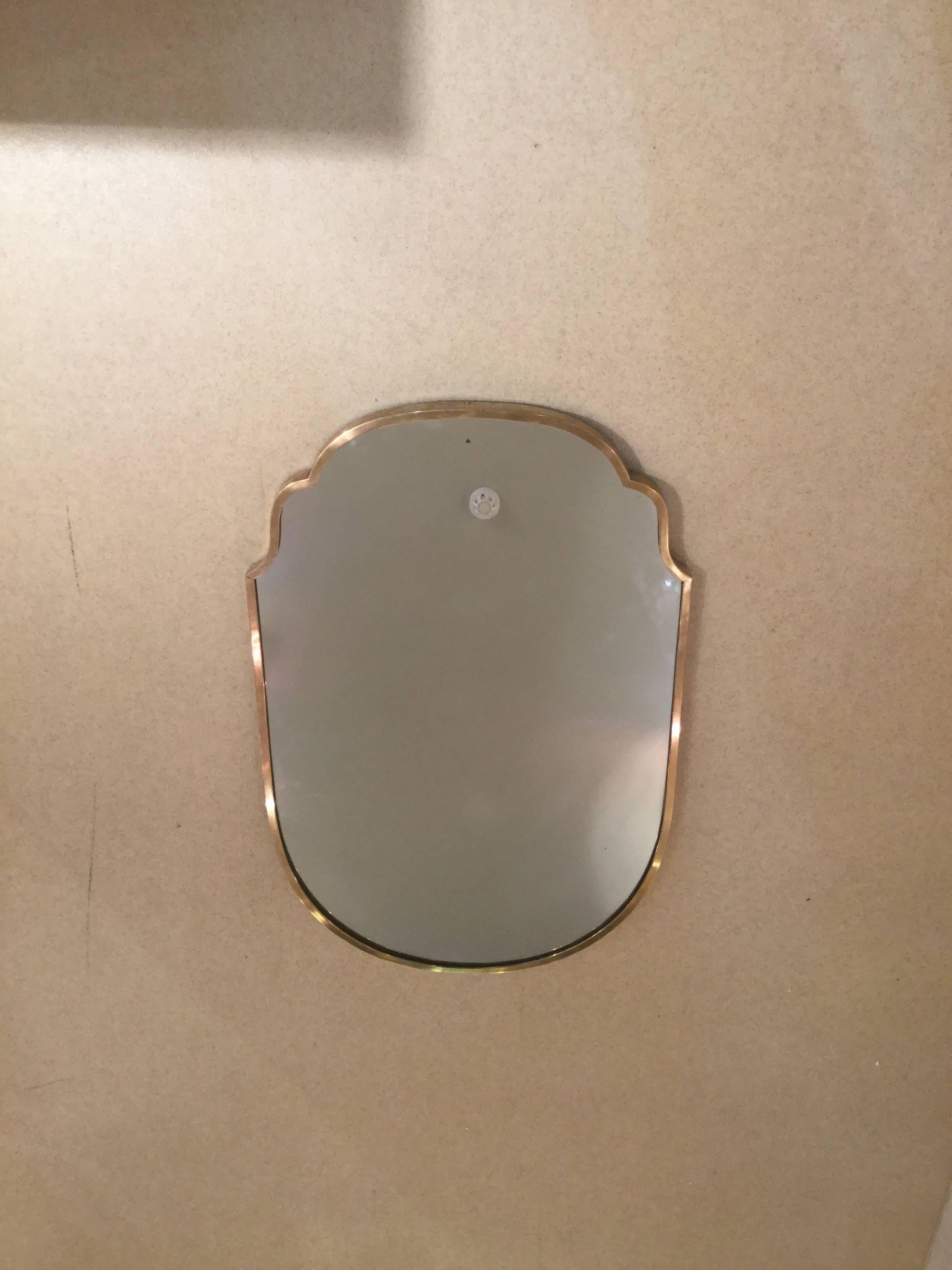A pair of 1960s mirror in the shape of a shield with a brass frame.
In good condition.
