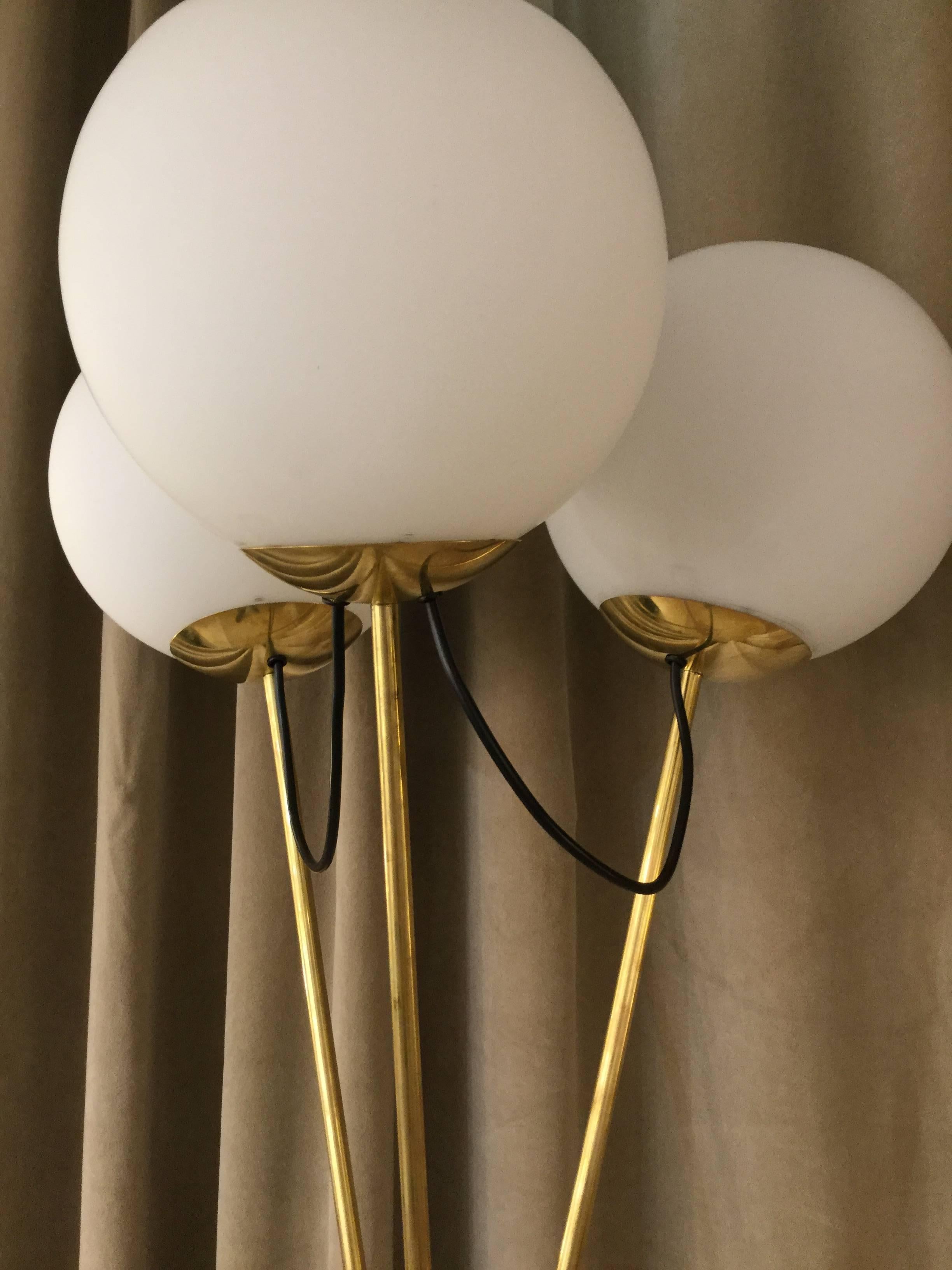 A pair of Italian designed floor lamps three spherical glass shades on brass tripod legs in the style of Stilnovo.
