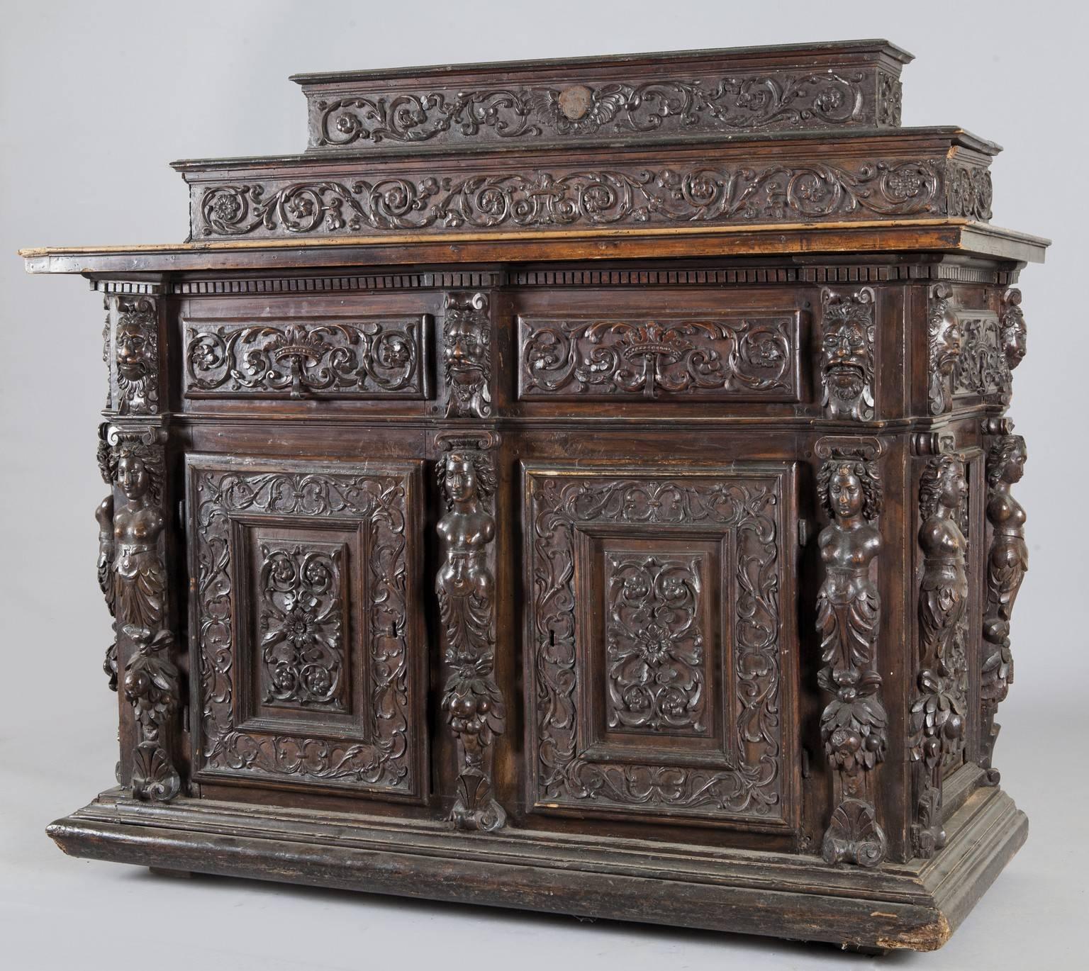 Large carved walnut credenza with two doors and two drawers, raised on two shelves, three front and side pilasters with two small drawers, Piedmont early 17th century.