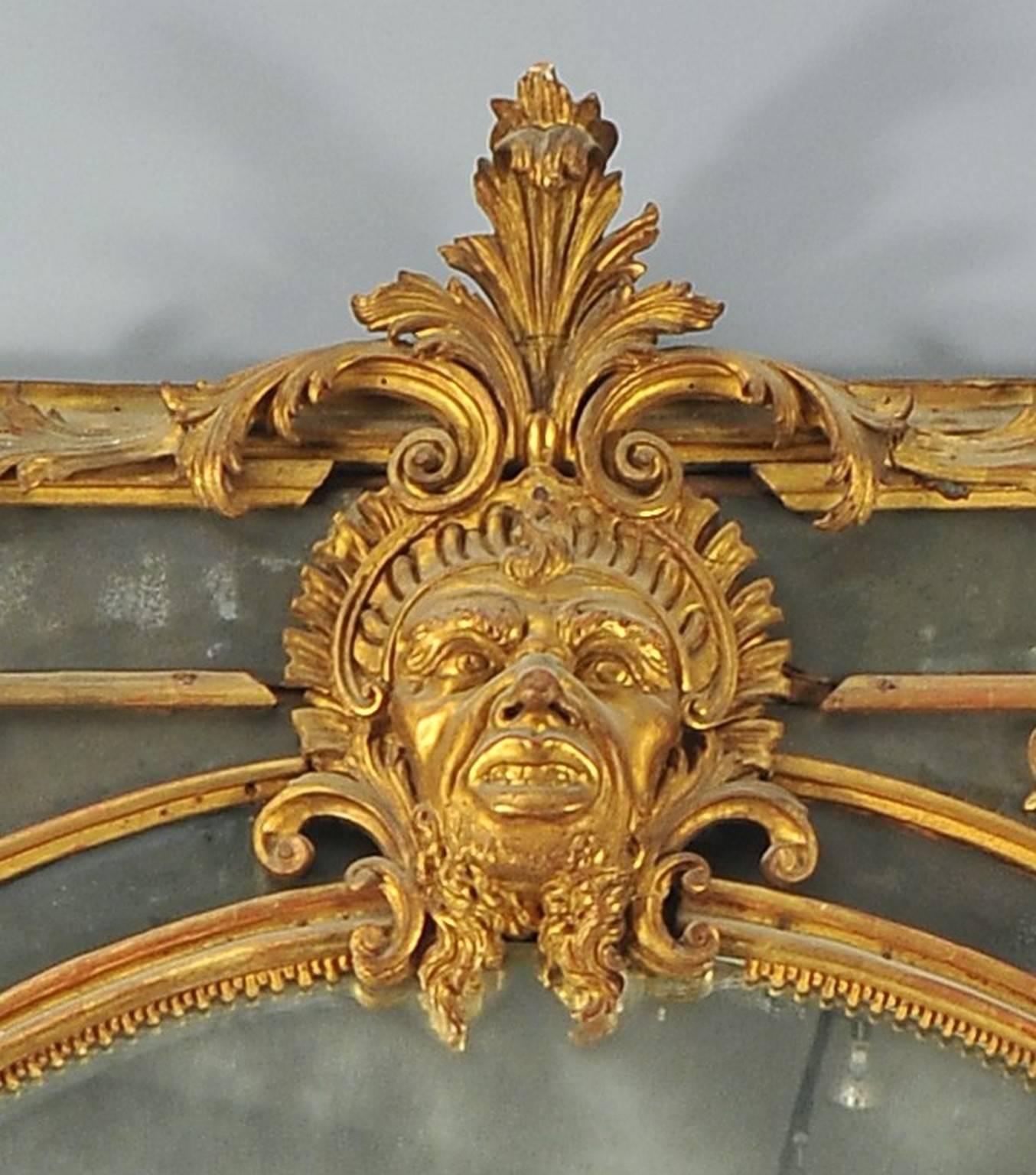 Mirror transition between Louis XIV and Louis XV in finely carved and gilded wood with a central mask. Original mercury mirror, Torino, first half of the 18th century.