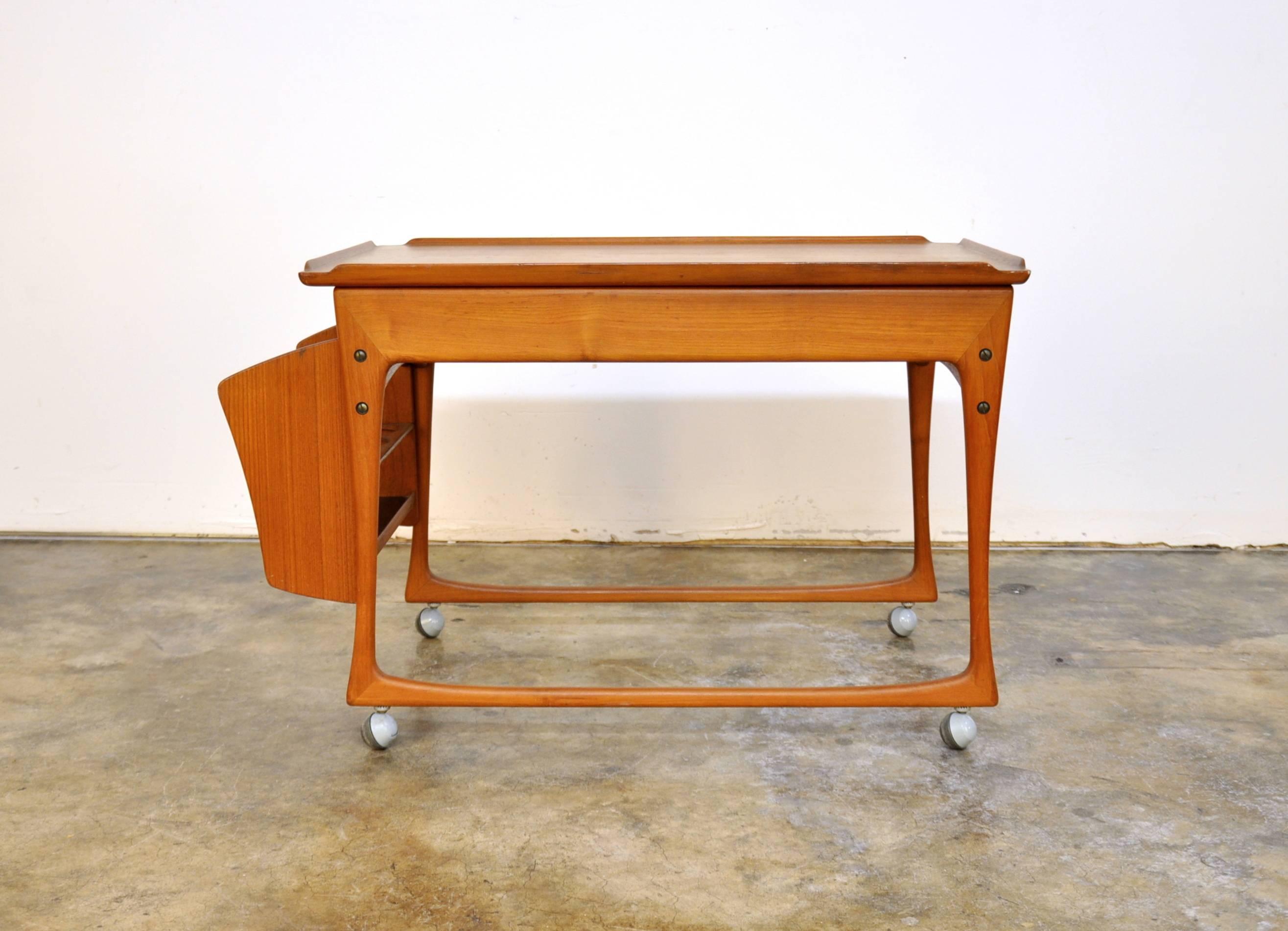 This stylish mid-century extending serving cart features a removable bottle holder which can be placed on either side, and dates from the 1960s. The sliding top opens to reveal a bar top interior allowing for additional storage and an expandable