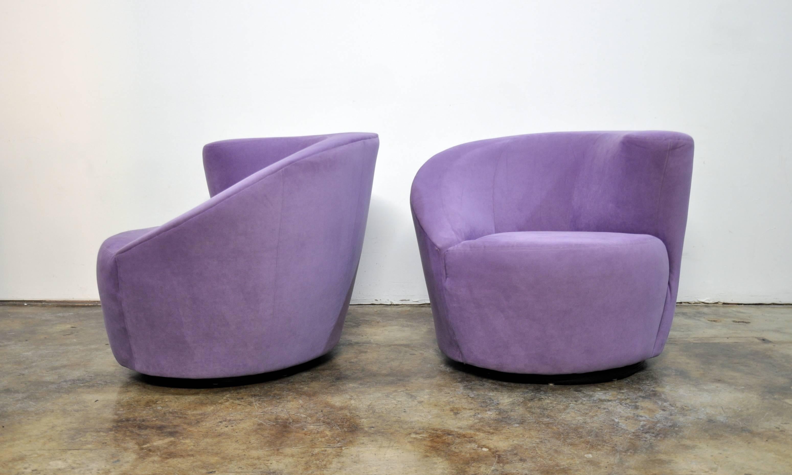 A vintage pair of the Mid-Century Modern Classic Kagan lounge chairs in their original lilac ultrasuede upholstery. The light purple chairs feature asymmetrical backrests and memory swivel. The ebonized wood swivel bases allow the club chairs to