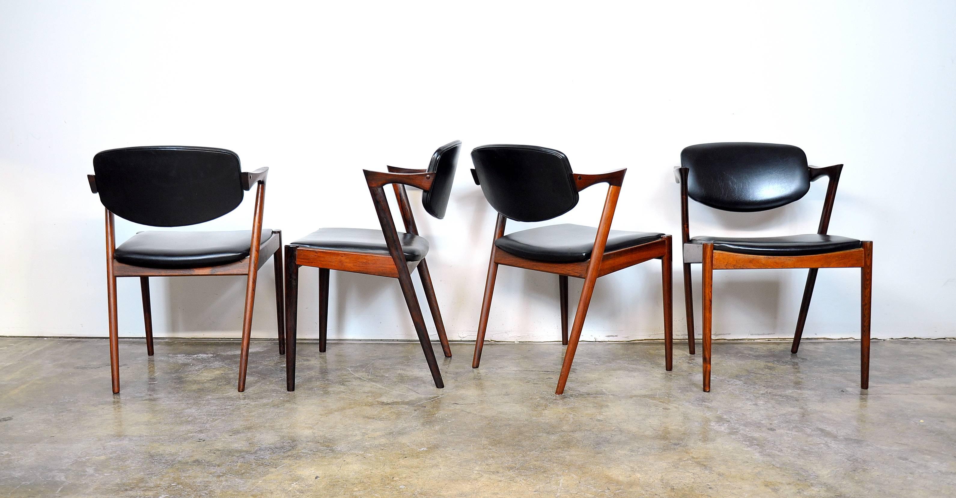 Striking set of Mid-Century Danish Modern rosewood model #42 dining armchairs designed by Kai Kristiansen for Schou Andersen, dating from the mid-1960s. The chairs feature stunning lines with masterful angles and curves, tilting backrests and