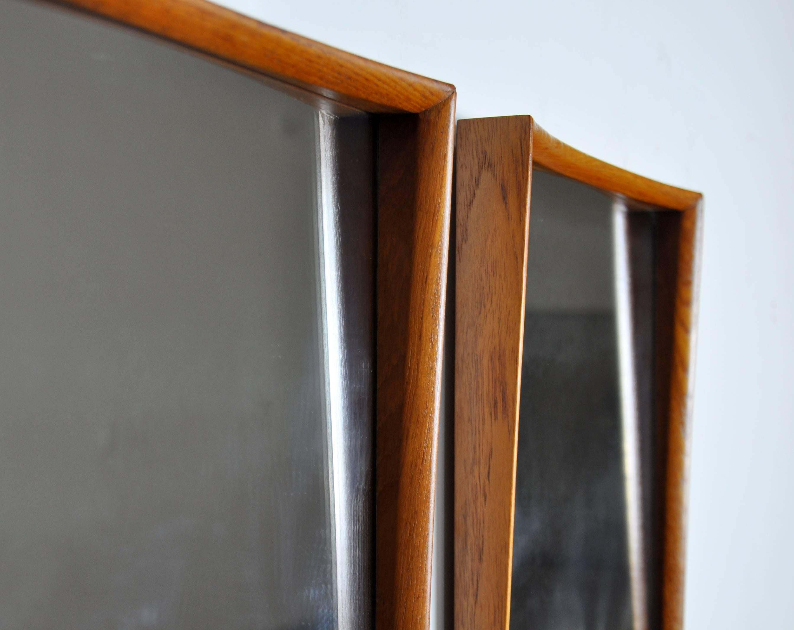 A gorgeous pair of vintage Danish Modern sculptural mirrors with teak frames, designed by Svend Aage Madsen for Falster Mobelfabrik and dating from the 1960s. The sleek frame of each mirror is beautifully sculpted. These could, when placed over a