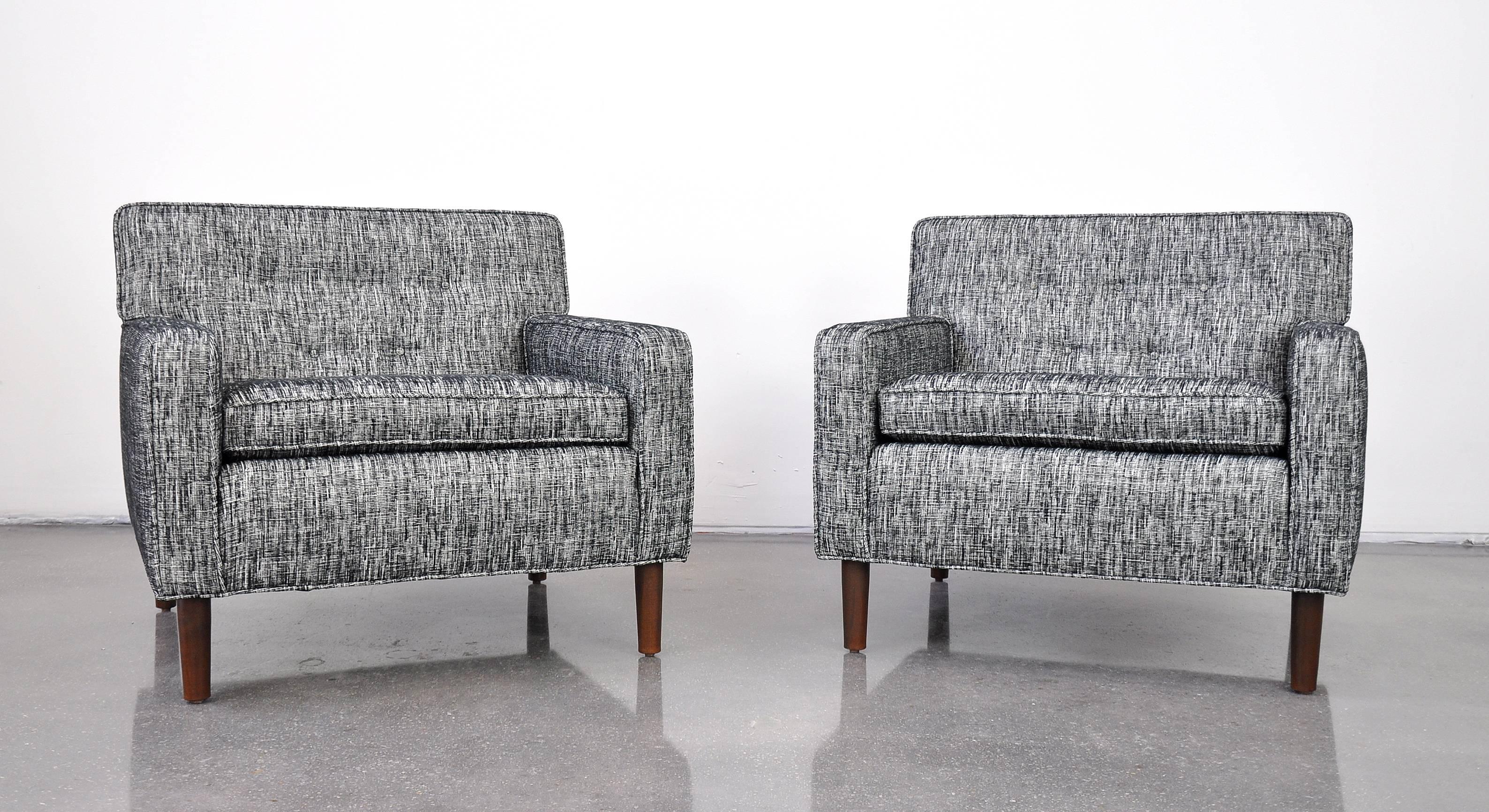 A handsome pair of Mid-Century Modern tufted club chairs dating from the 1950s, attributed to Edward Wormley for Dunbar. Newly reupholstered and very comfortable. The chairs are raised on walnut tapered legs.