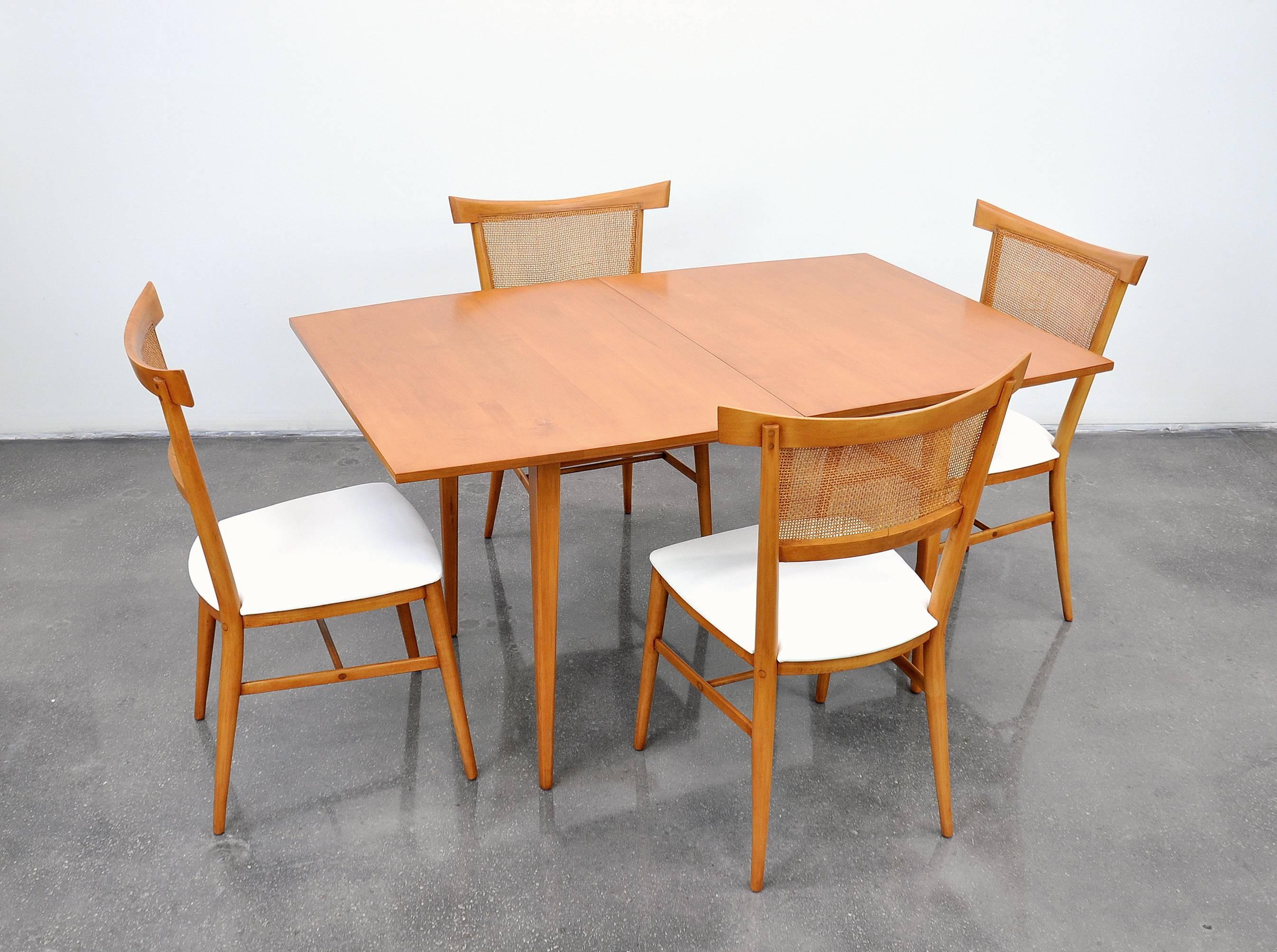 This striking Mid-Century Modern maple dining set was designed by Paul McCobb for the Perimeter Group line in circa 1957 and manufactured by Winchendon Furniture. Completely restored, it features an expandable boat-shaped table and four dining