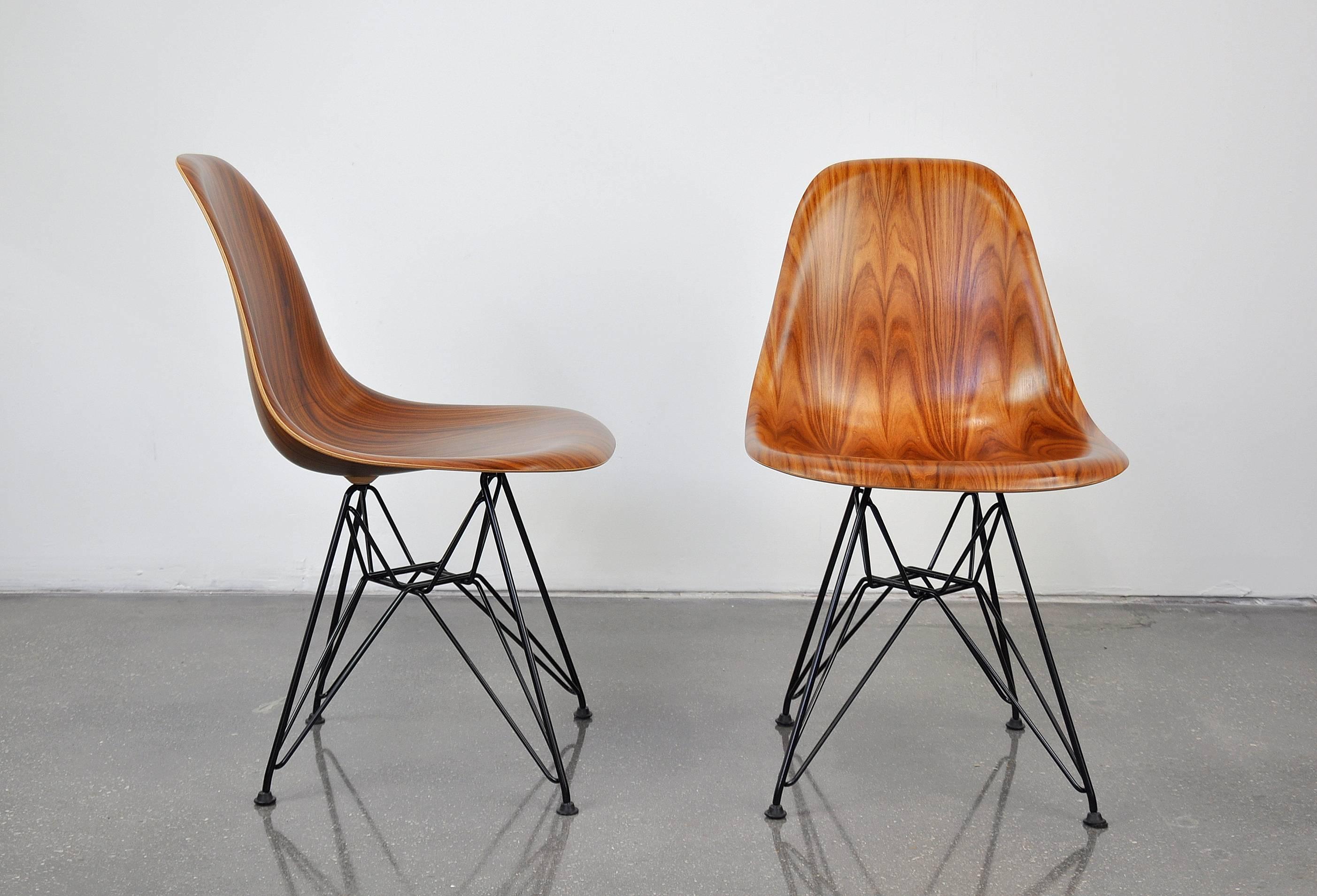 A gorgeous pair of Mid-Century Modern DWSR shell chairs designed by Charles and Ray Eames for Herman Miller. The pair of dining or side chairs feature molded Santos Palisander wood (similar to rosewood) shells and black wire base. Works well as