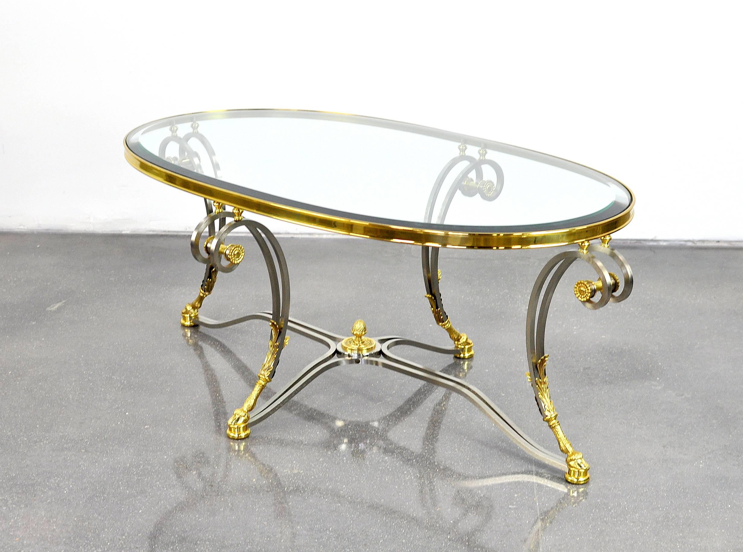 A gorgeous vintage La Barge model LT0390 Louis XVI cocktail table in polished steel and brass, with inset bevelled glass top. The oval table features ram's feet, pine cone finial, rosettes and scrollwork, in typical neoclassical fashion. A wonderful