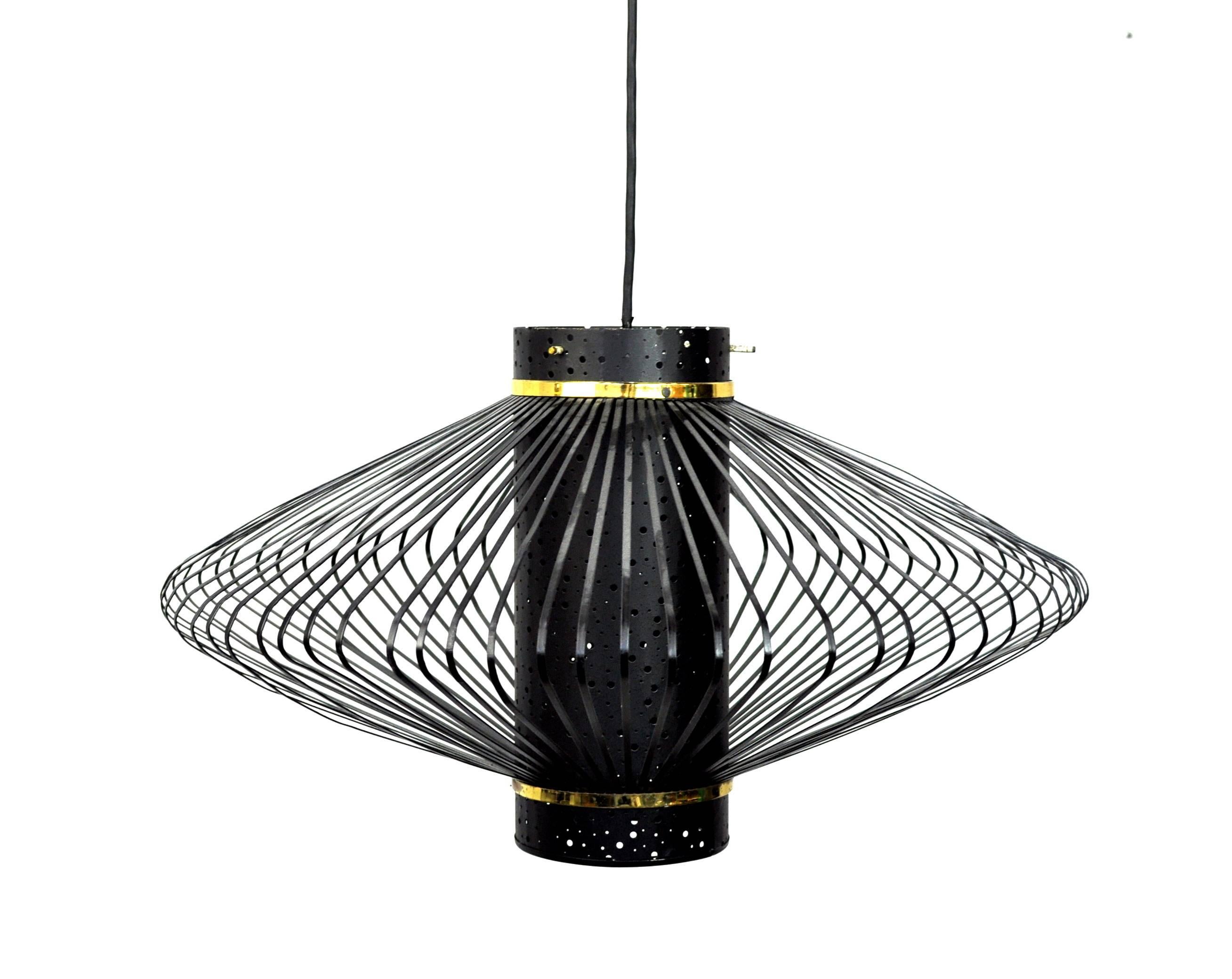 Brass and black enameled metal vintage pendant light fixture. The mid-century modern lamp features a perforated canister surrounded by a saucer shaped metal cage with solid brass accents. A very decorative and unique 1950s chandelier! This is