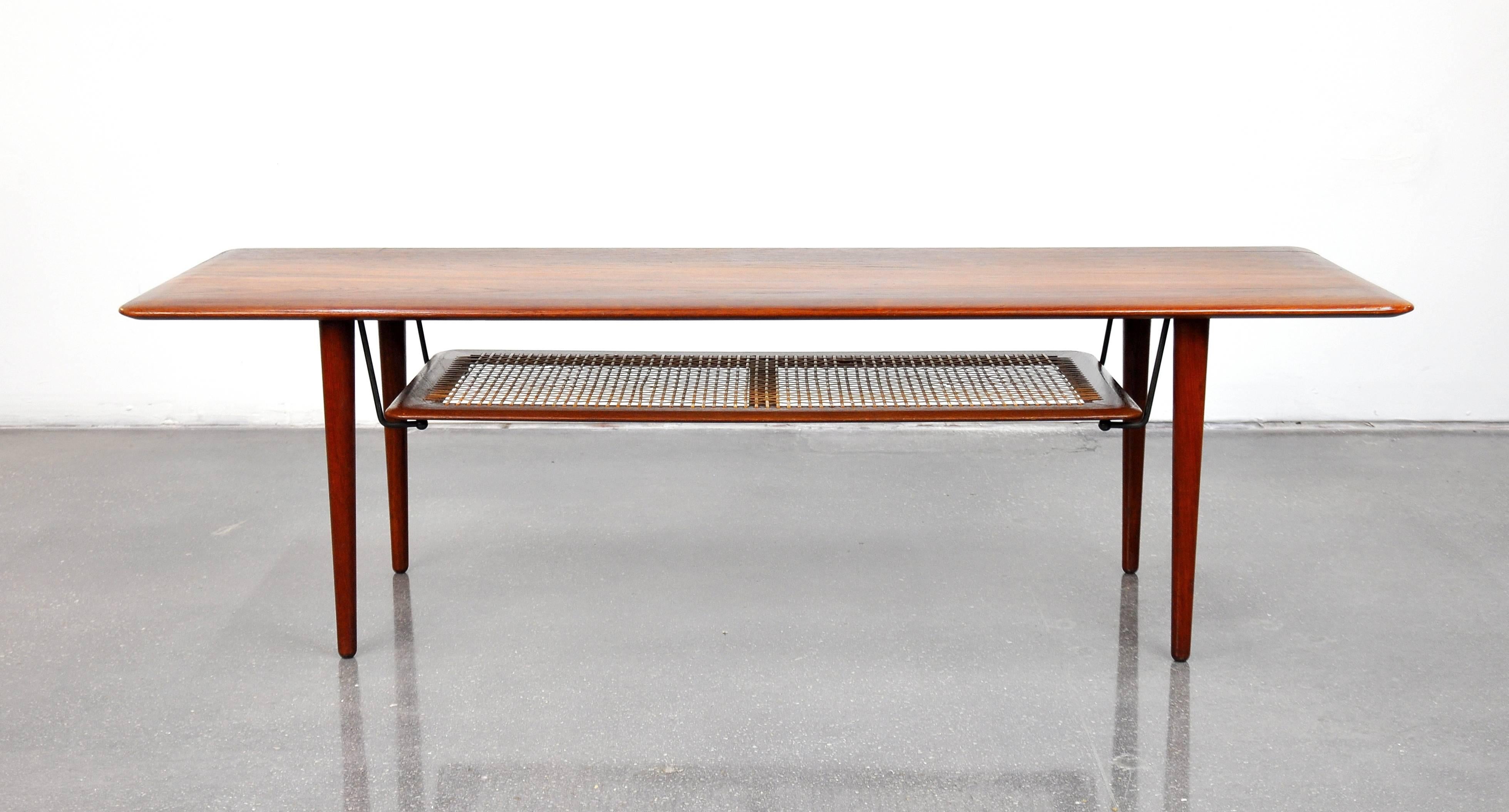 A vintage Danish Modern two-tiered cocktail table, model FD516, designed in 1956 by Peter Hvidt and Orla Molgaard Nielsen for France and Daverkosen (which became France and Son). The solid teak top and legs connect with brass angled supports to a