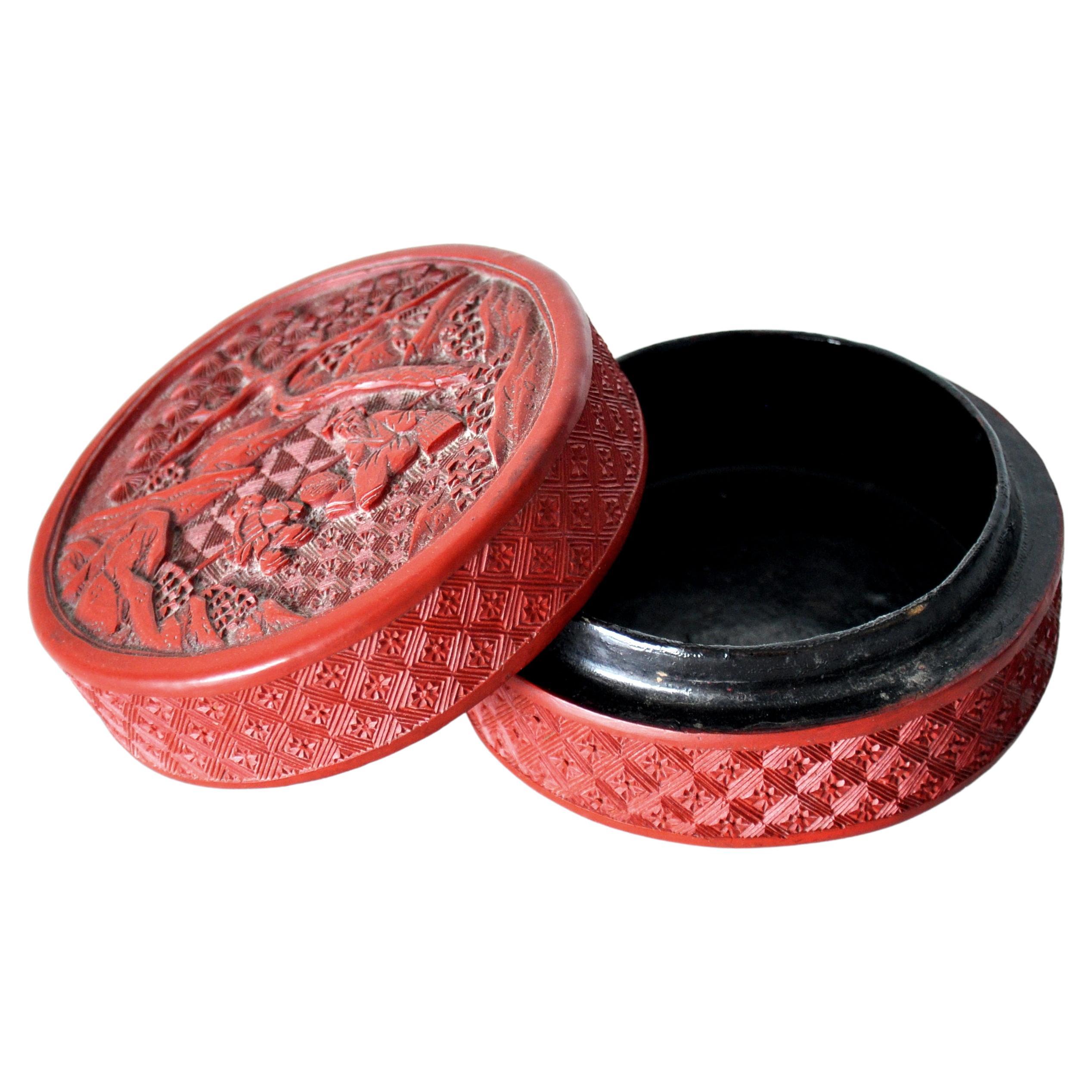 A fine antique Chinese red cinnabar lacquer lidded round box carved with a scene with a young boy and a seated elderly bearded sage within a rocky landscape with trees. The 