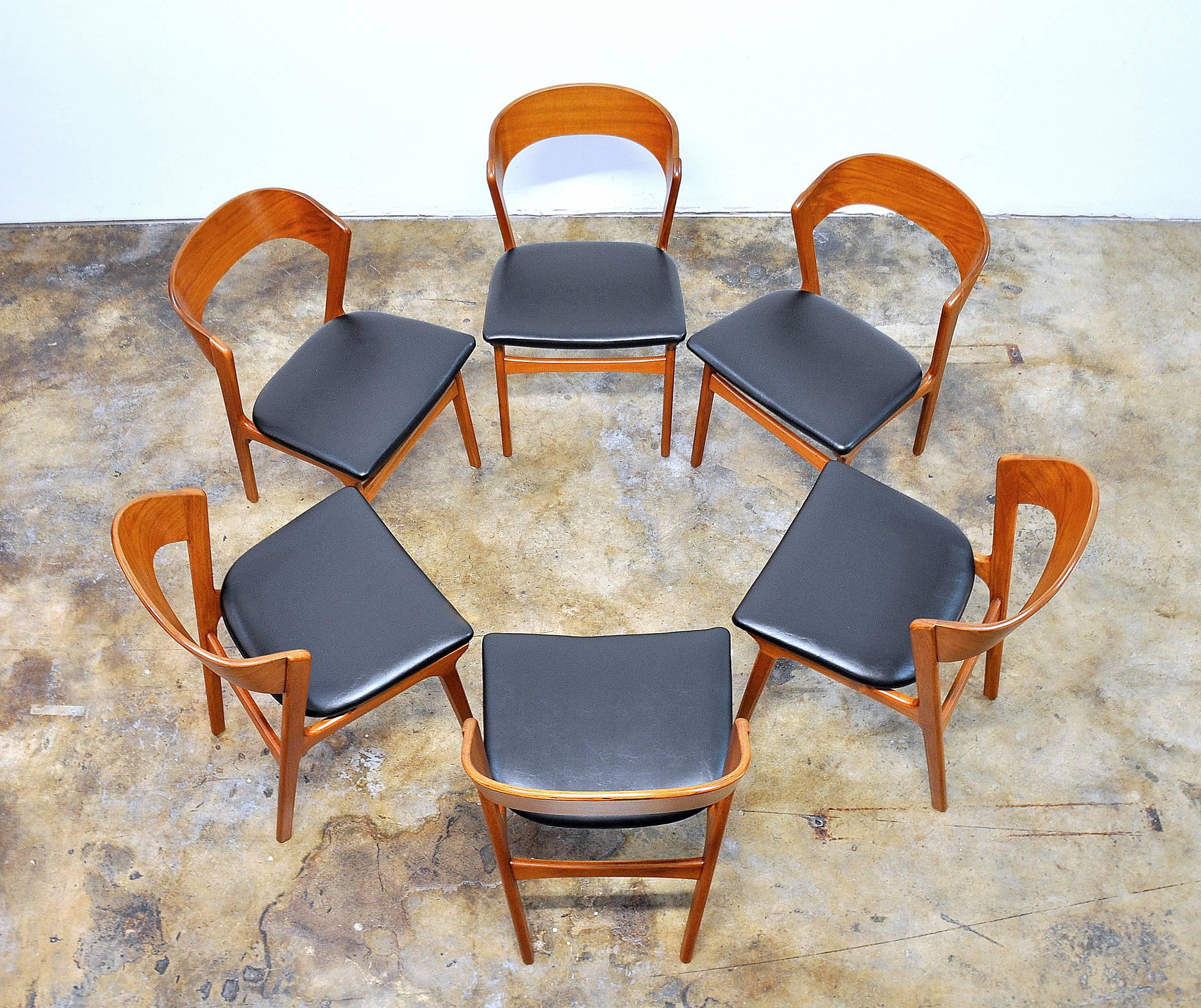 Stunning set of one owner mid-century Danish modern solid teak chairs with curved and slanted ribbon backrests for unparalleled comfort and striking lines. The chairs have been refinished, and the seats recovered in period correct, soft, black faux