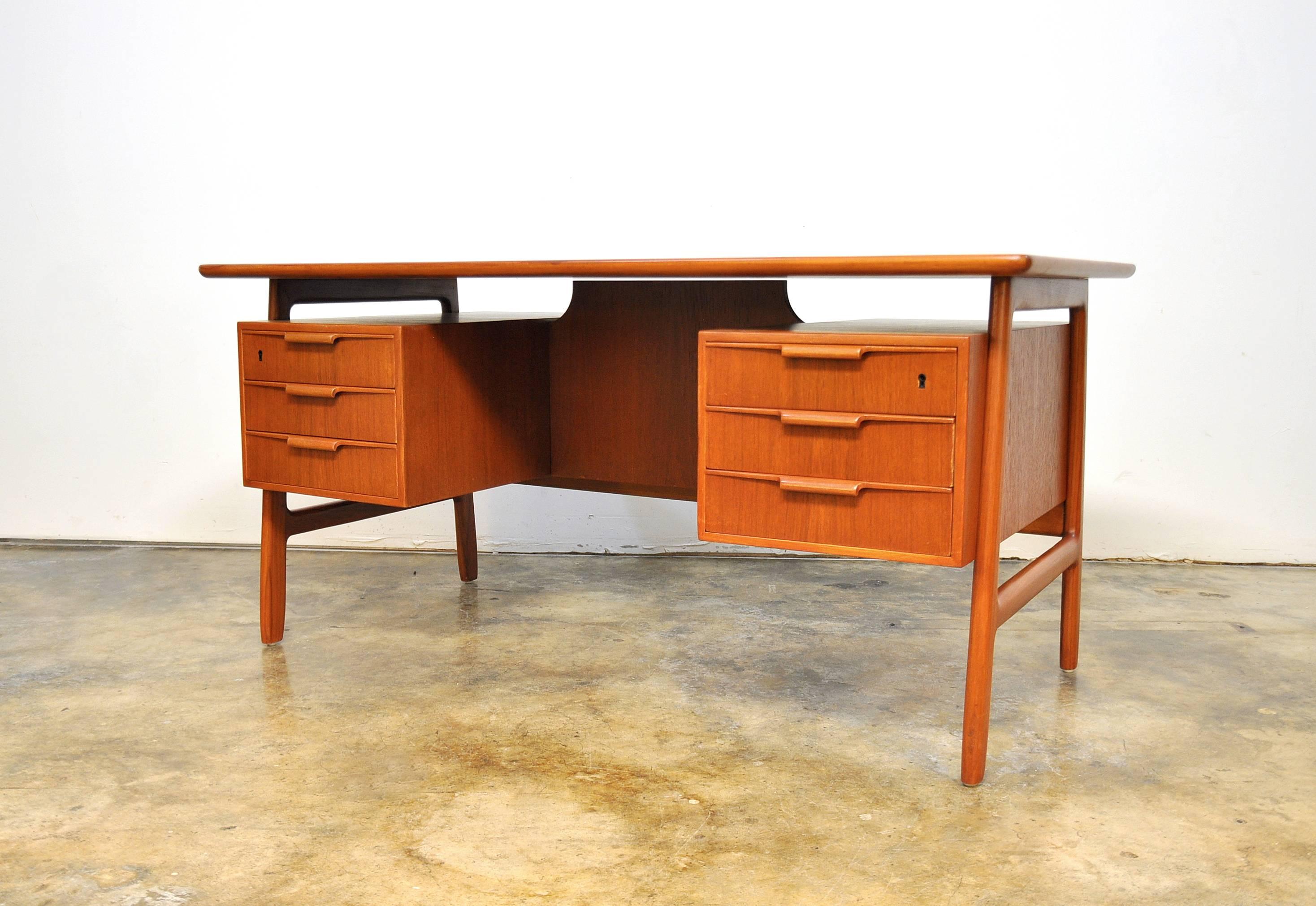 Splendid Mid-Century Danish modern model 75 executive desk dating from the 1960s. The refinished vintage desk features six drawers with sleekly sculpted wood pulls. Additional storage space is found on the backside with two open bookshelves and a