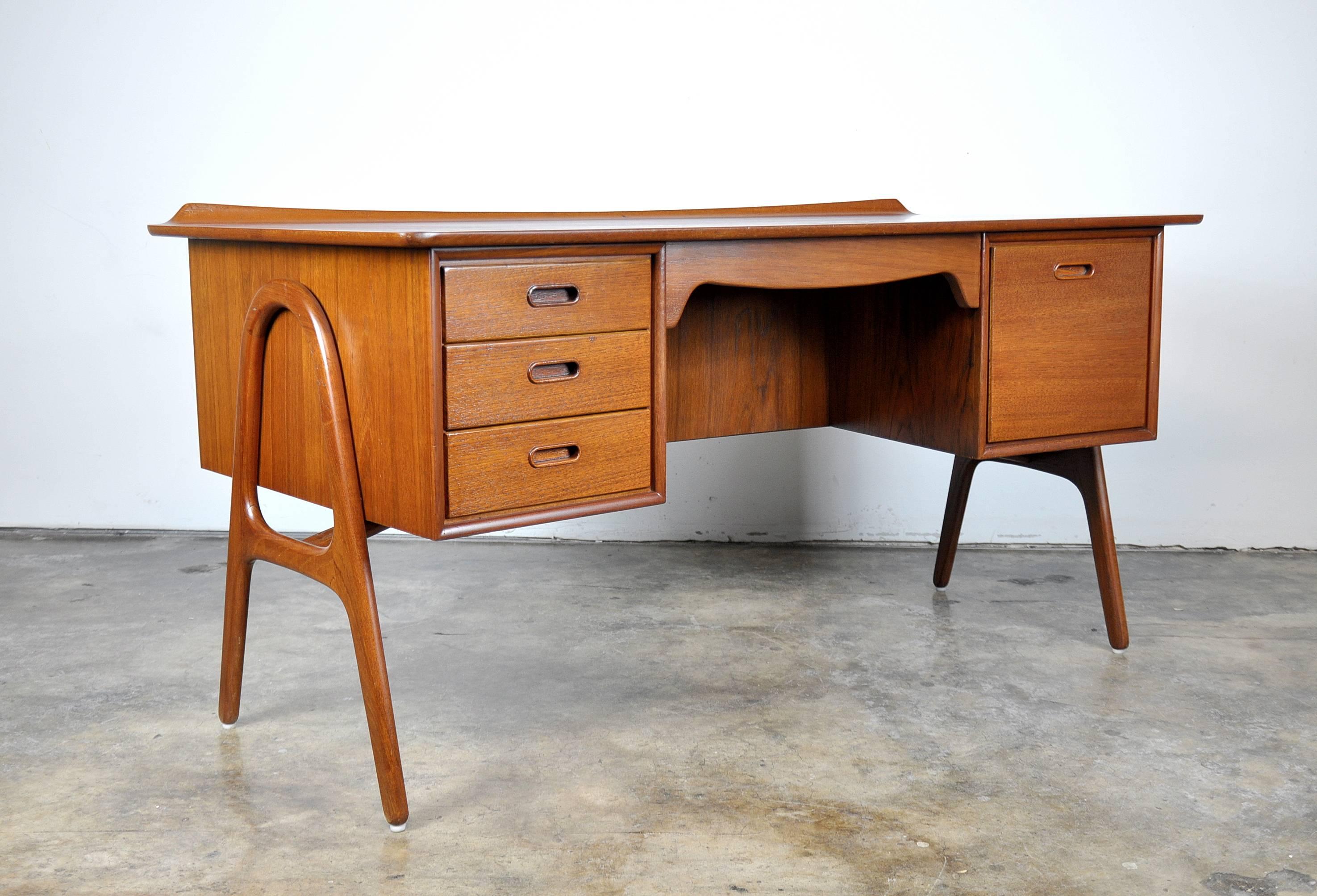 A gorgeous newly refinished Mid-Century Modern executive desk designed by Svend Aage Madsen and manufactured by Sigurd Hansen Mobelfabrik in the 1960s. The curved and beautifully sculpted desk features four drawers, one of which is for files and a