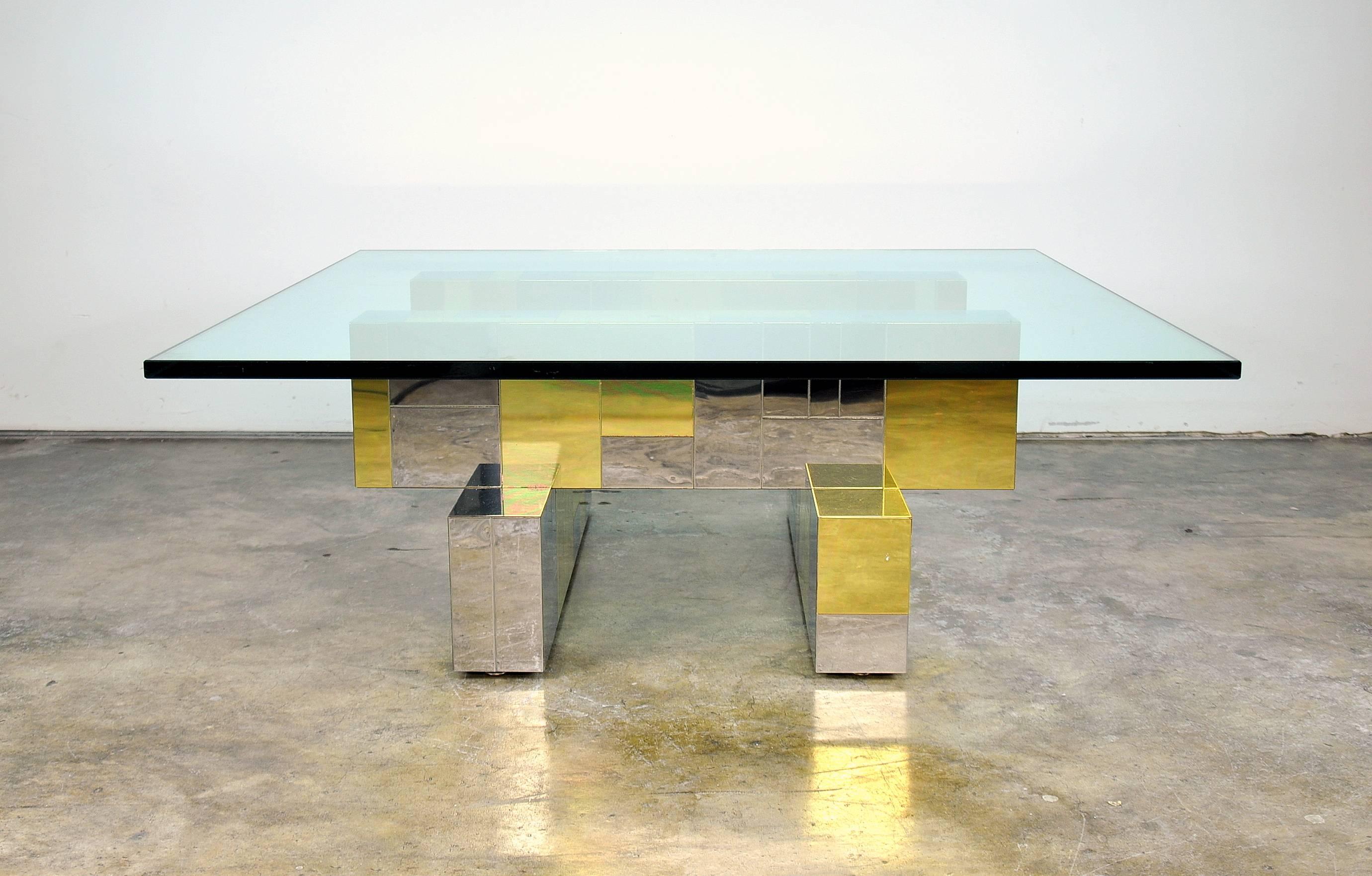 A vintage Mid-Century Modern cocktail table dating from the 1970s. Designed by Paul Evans for Directional, it features a stacked base decorated with his iconic Brutalist brass and chrome patchwork, supporting a three quarter inch thick micro beveled