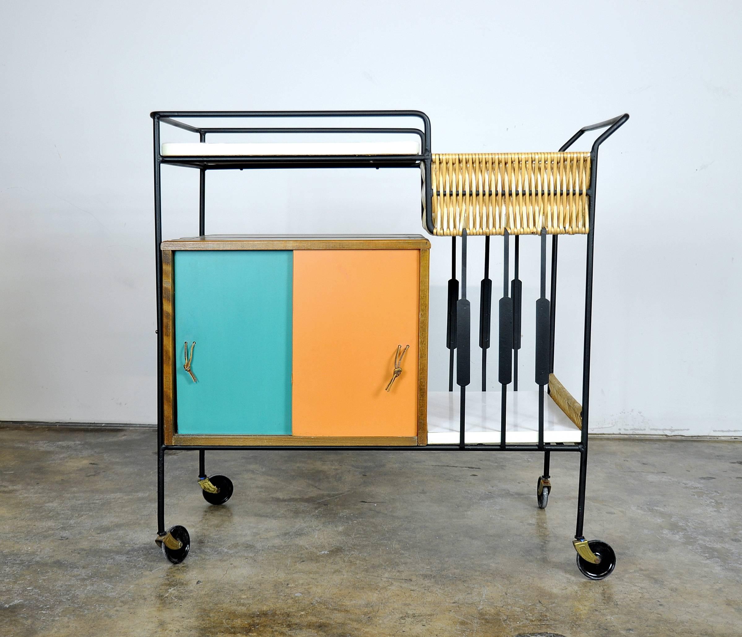 Lovely Mid-Century Modern vintage rolling bar cart designed by Arthur Umanoff for The Elton Company in circa 1952. The serving tea trolley features colorful turquoise and orange sliding doors with leather pulls, slatted wood portions, white bar top