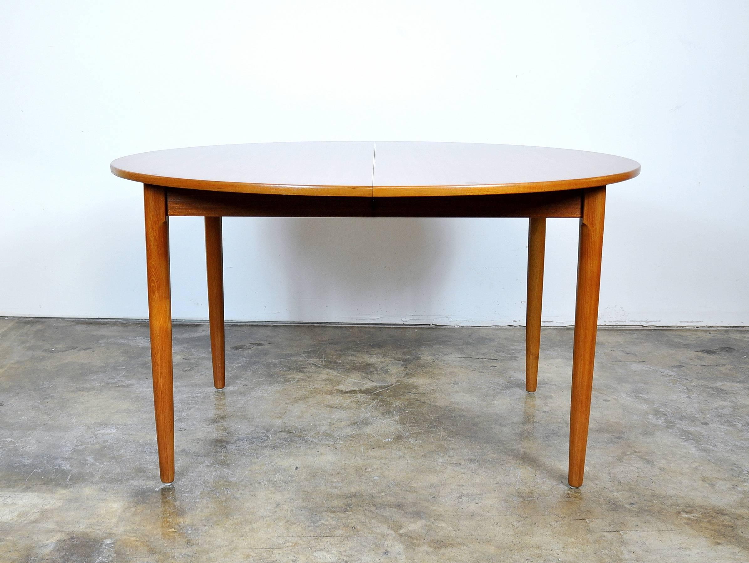 A Mid-Century Danish Modern round dining table manufactured in Denmark by Falster and dating from the 1960s. The table has been professionally refinished and exhibits beautiful grain patterns. It seats four when compact, but can be extended with a