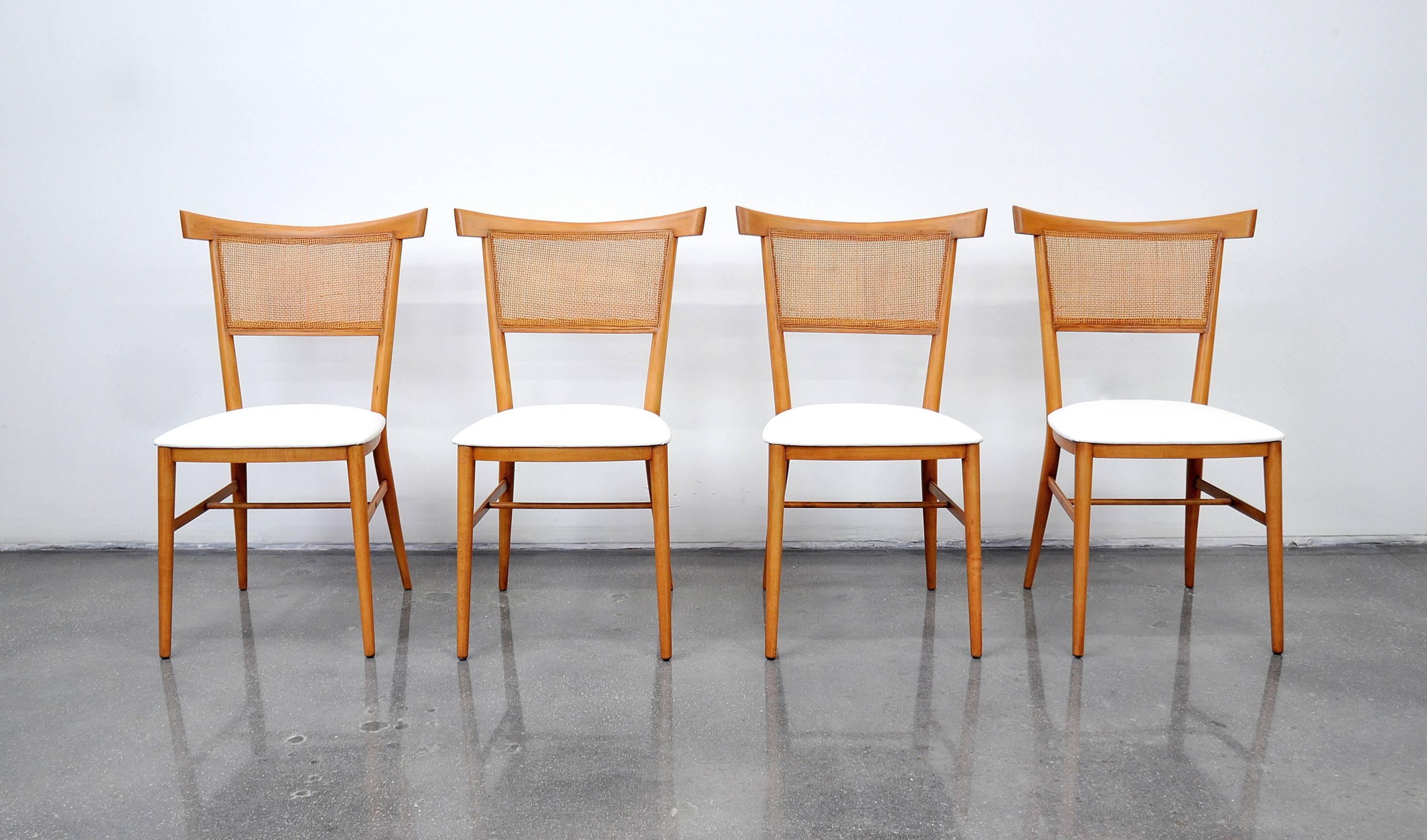 Striking set of four Mid-Century Modern maple dining chairs designed by Paul McCobb for the Perimeter Group line in, circa 1957 and manufactured by Winchendon Furniture. The caned backs feature a distinctive bowtie shaped top rail. The seats have