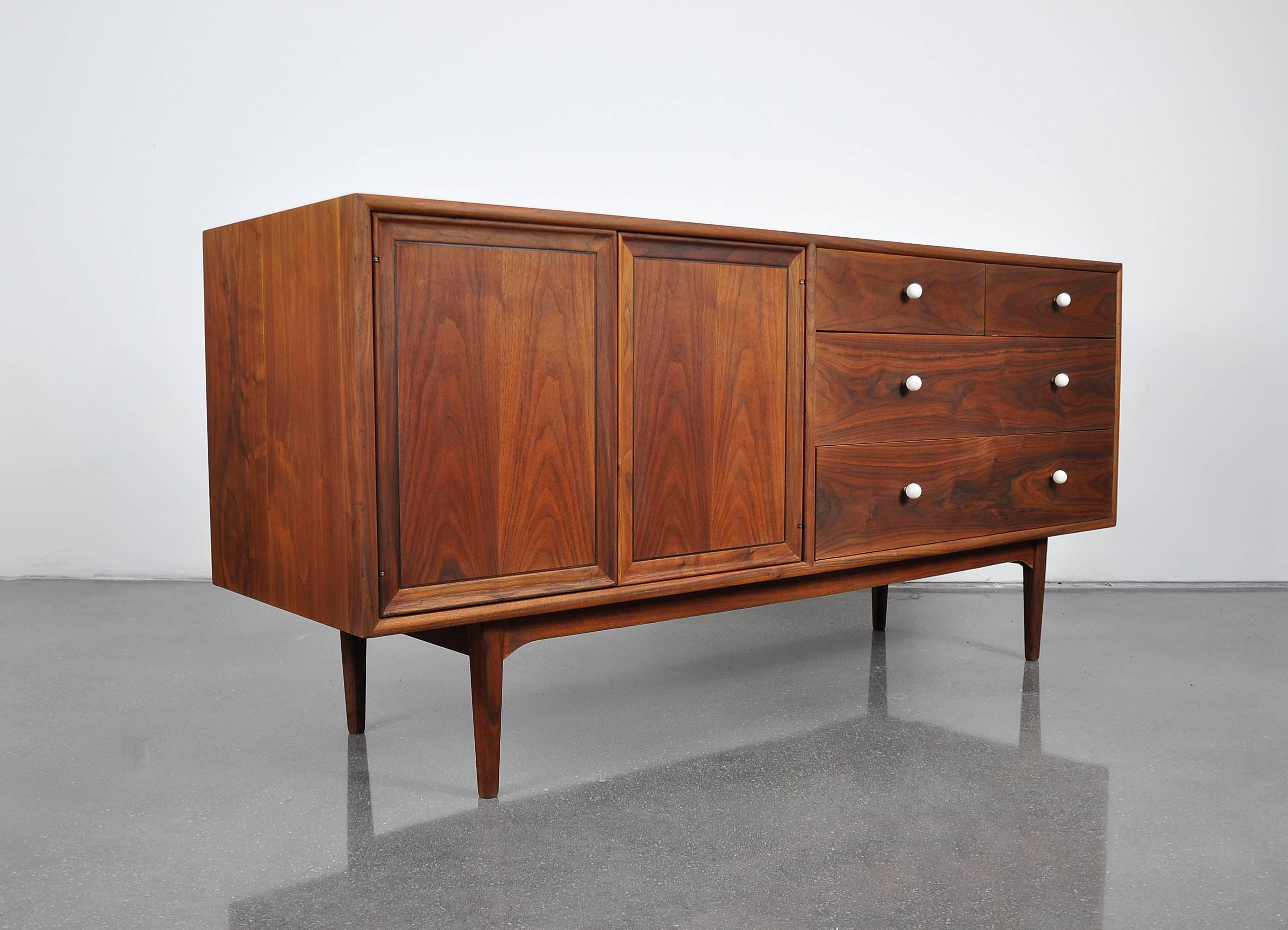 A gorgeous Mid-Century Modern walnut triple dresser from the desirable declaration line designed by Kipp Stewart and Stewart MacDougall for Drexel in the 1950s. The credenza features gorgeous wood grain patterns and the original signature white