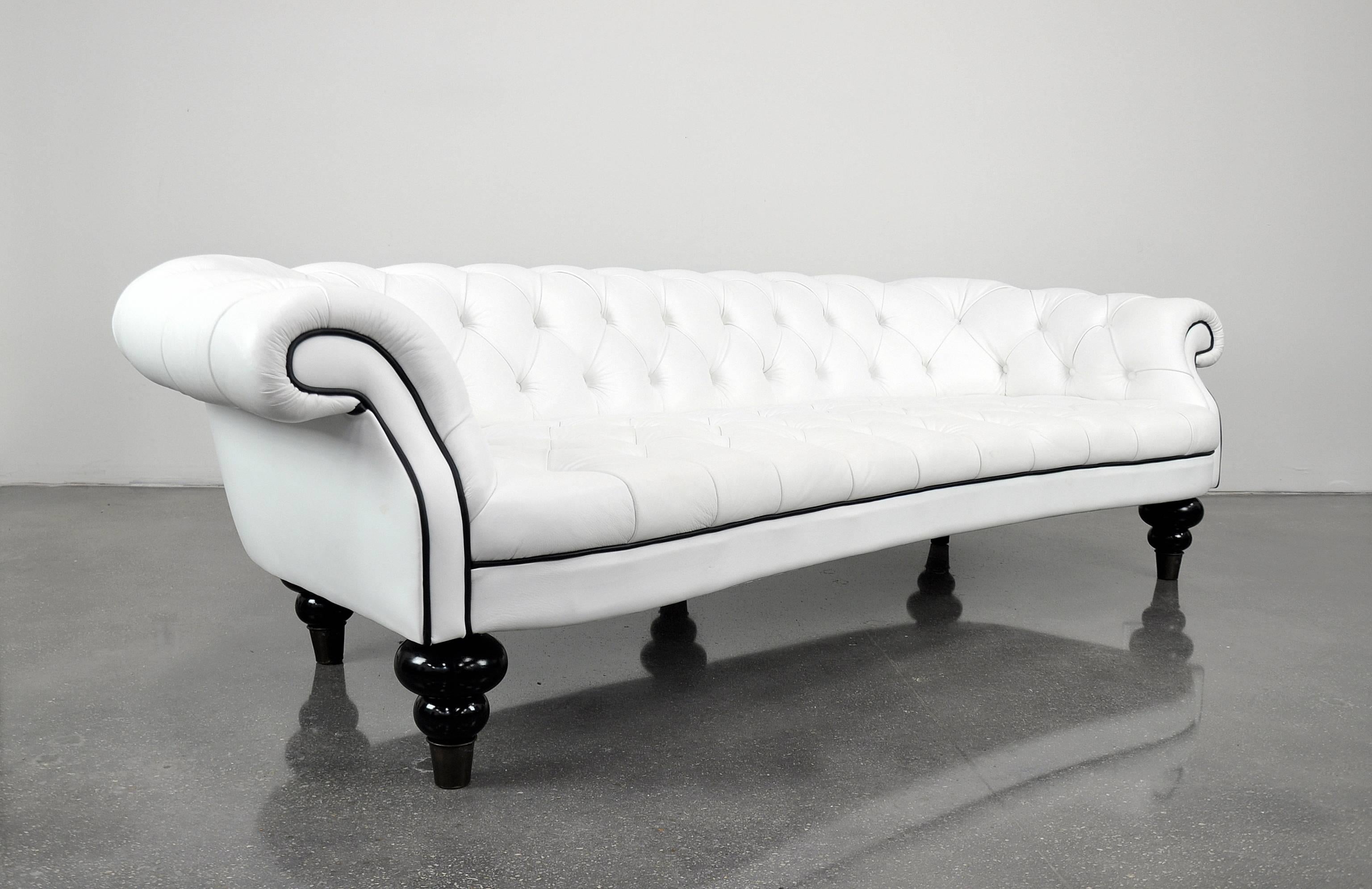 A limited edition tufted Vincent sofa, designed by Romeo Sozzi and custom made by the Italian master furniture maker Promemoria. The long, curved couch rests on five black lacquered turned wood legs with large solid brass caps. The sofa, originally