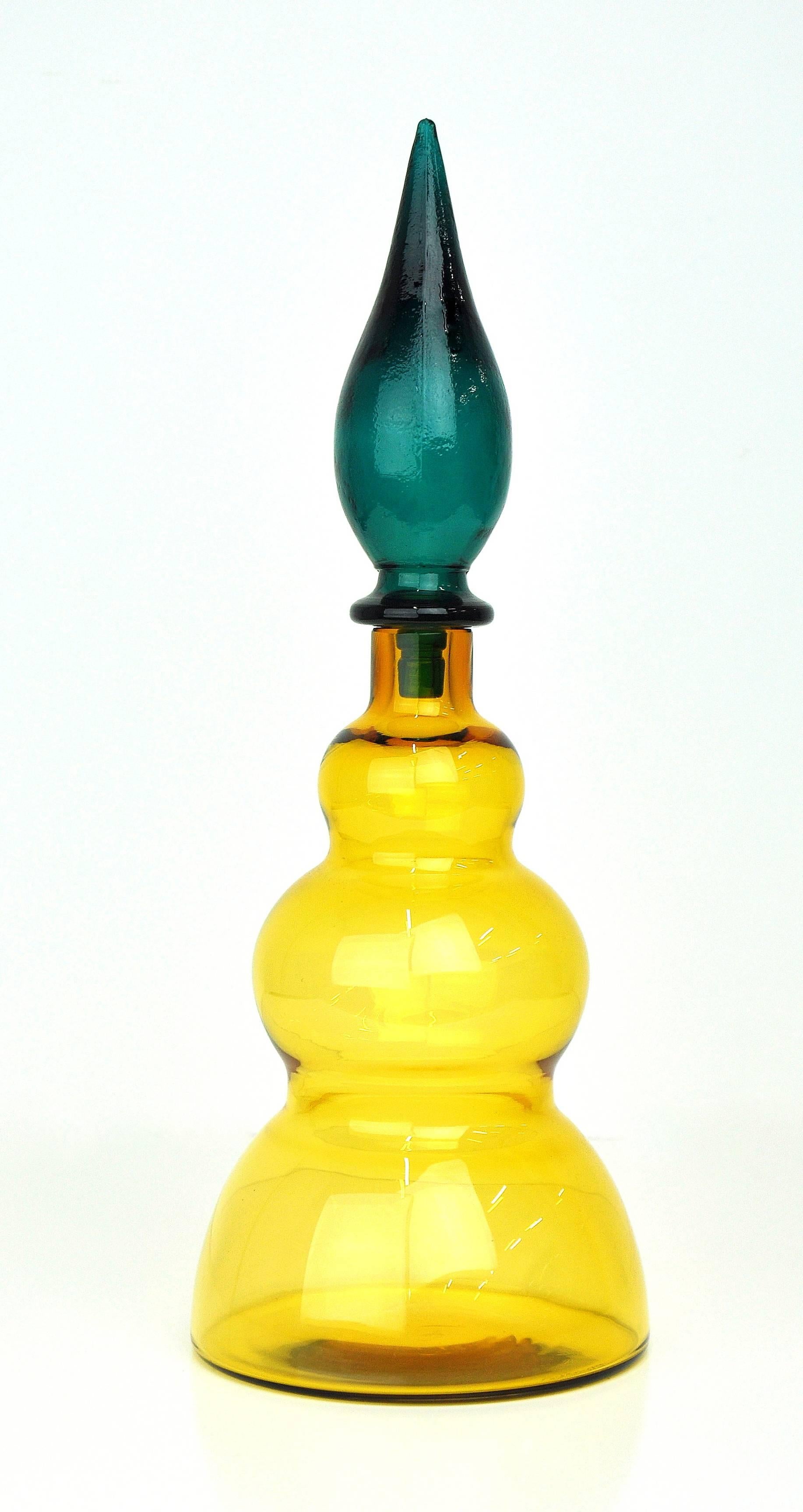 This vintage Italian Mid-Century Modern Venetian gourd shaped art glass genie bottle features a clear amber yellow color and a rich and mesmerizing emerald green colored associated stopper. Manufactured by Salviati, the bottle dates from the 1960s.