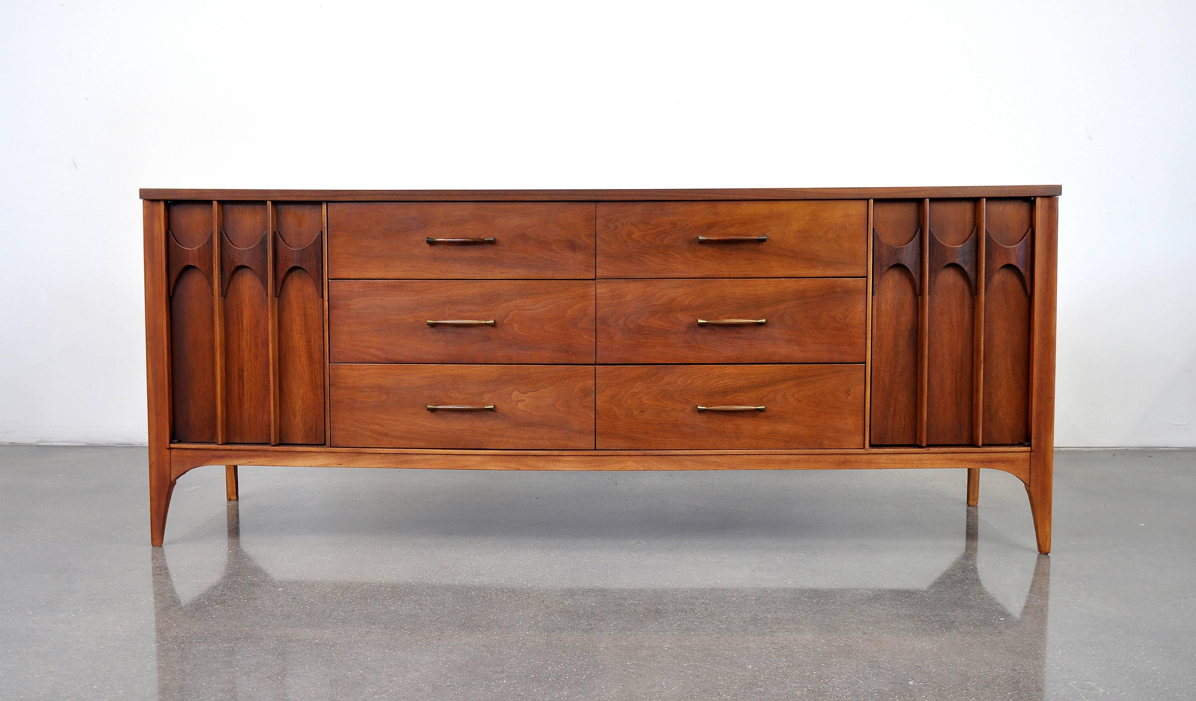 Beautiful vintage Mid-Century Modern extra long, 12 drawer credenza. It features beautifully grained, bookmatched walnut, signature sculpted, relief carved rosewood accents on the cabinet doors, and tons of storage space. The piece can be used in a