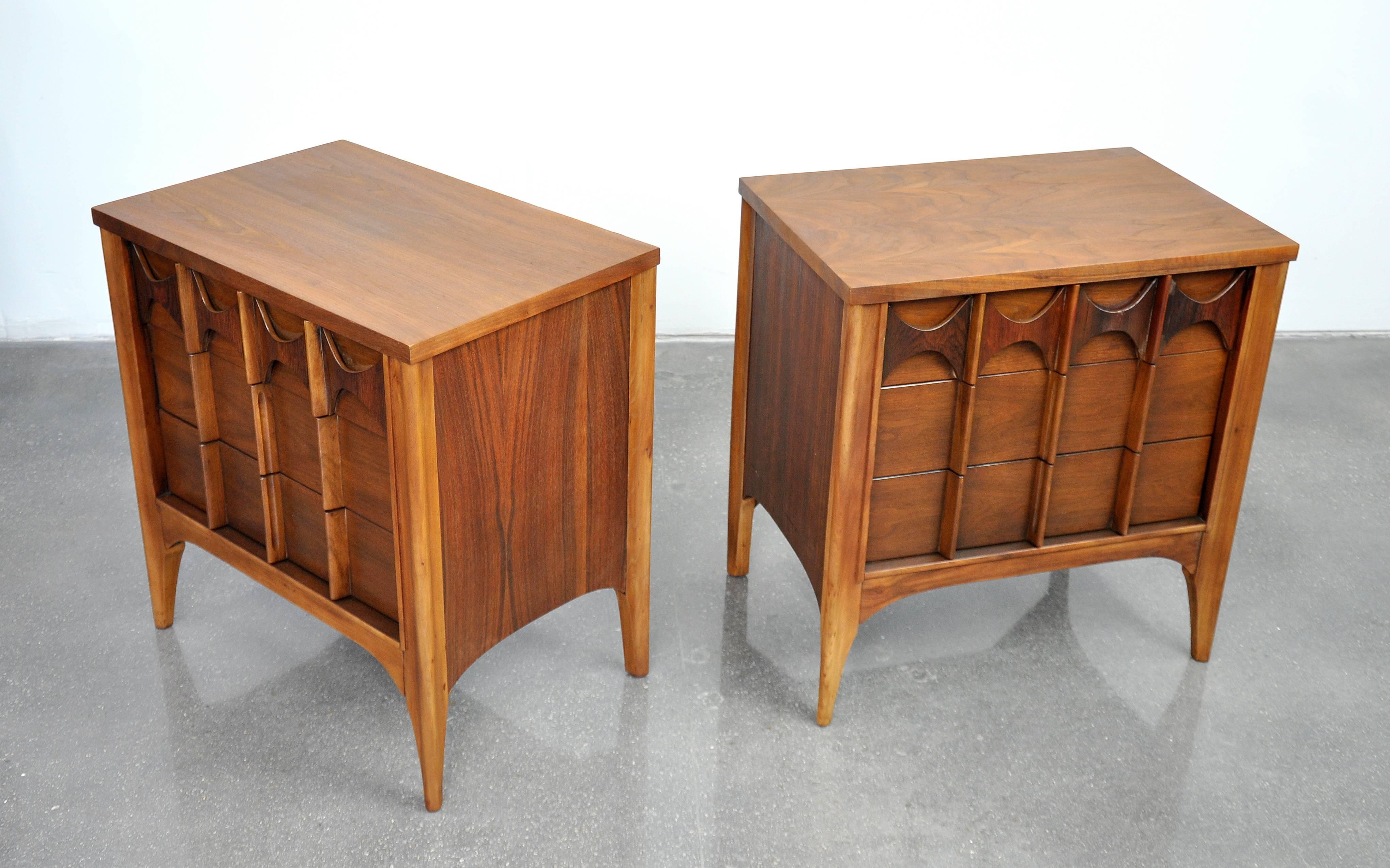 Beautiful pair of vintage Mid-Century Modern bedside tables. Each night stand features three drawers with beautifully grained, bookmatched walnut and signature sculpted, relief carved rosewood accents. Could also be used as side or end tables.