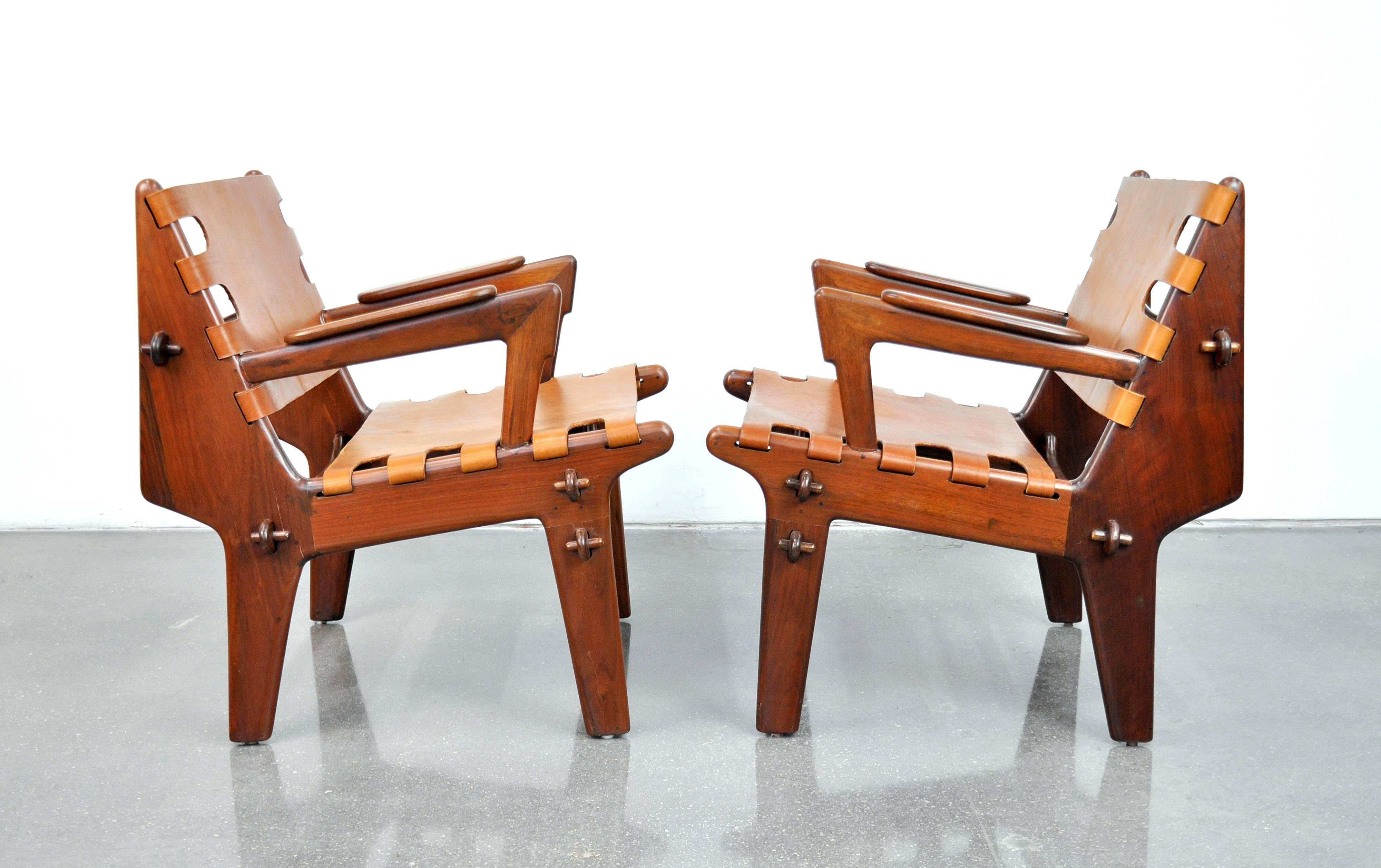 Amazing pair of vintage Mid-Century Modern safari style easy lounge chairs by Ecuadorian designer Angel Pazmino. The sculptural rosewood frames are slung with newer caramel colored leather and feature a wooden peg construction that allows the pieces