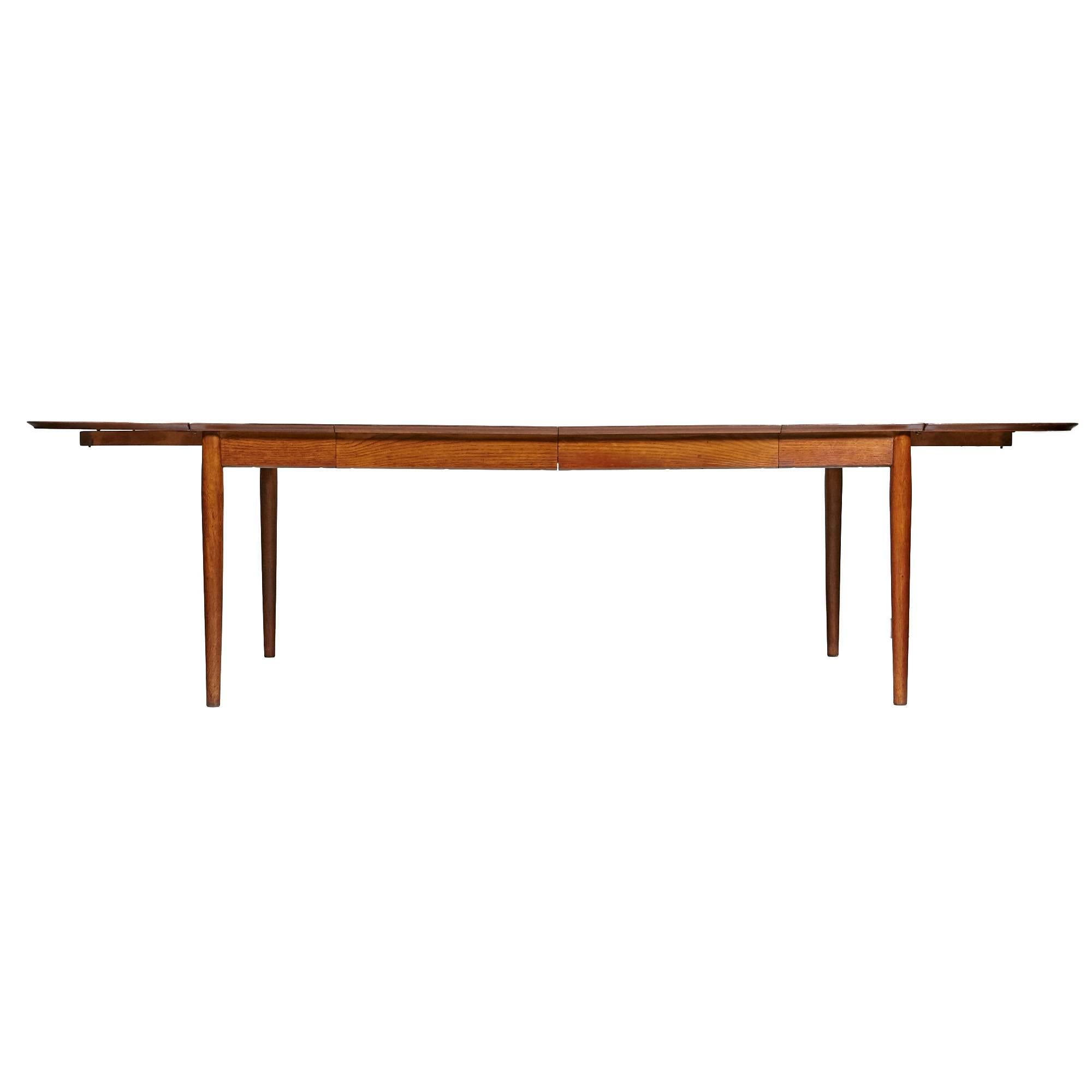 Danish 1950s Arne Vodder designed for the George Tanier Selection teak extension dining table manufactured by Sibast Mobler. The table features two rounded removable drop-leaves with two additional insert leaves, a banded edge and round tapered