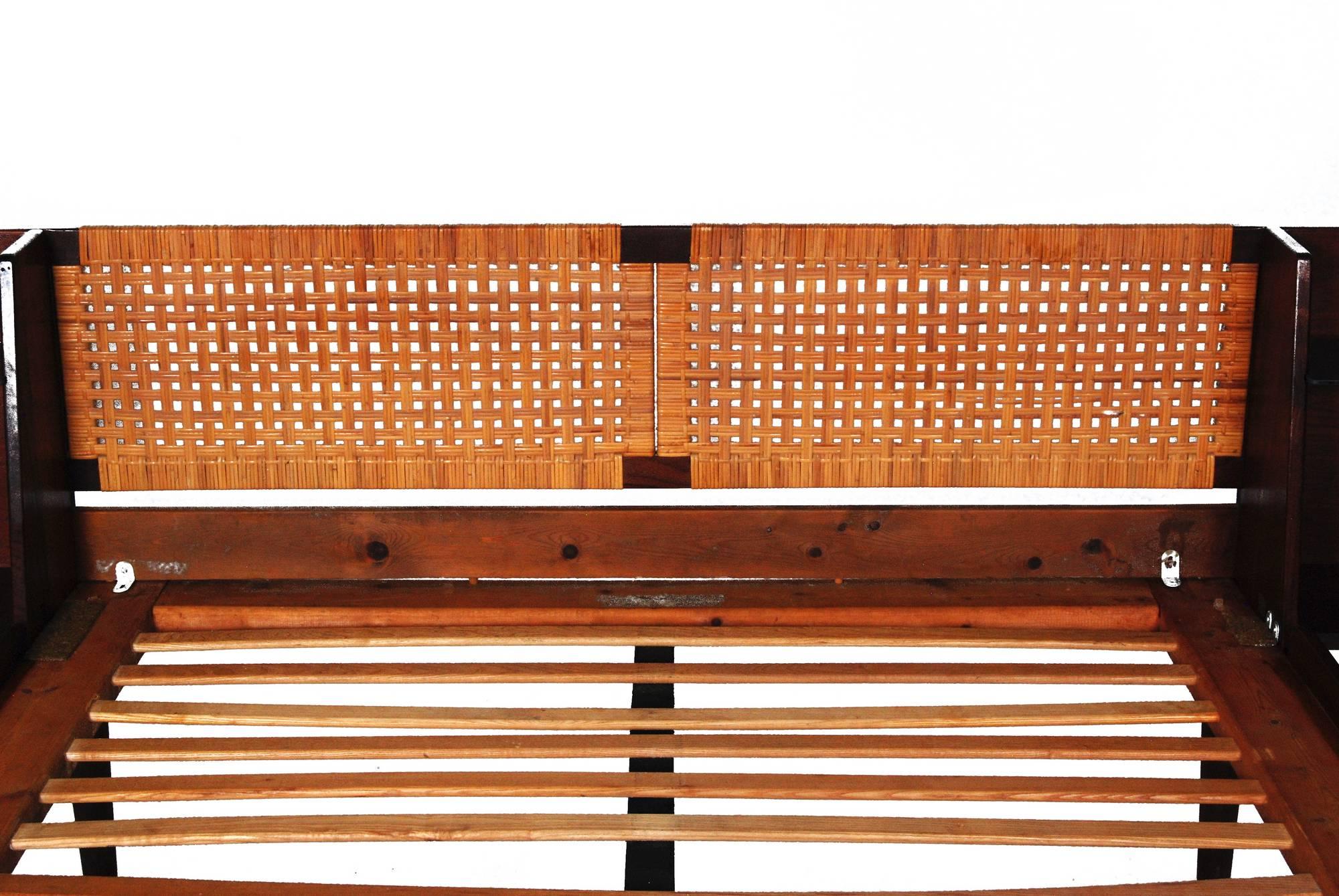 Rare 1960s Hans J. Wegner designed queen teak bed with caned headboard and black leather footboard for GETAMA, Denmark. The bed has built-in night tables with new smoked glass shelves. Caning, leather, and glass are perfect. One side rail has spot