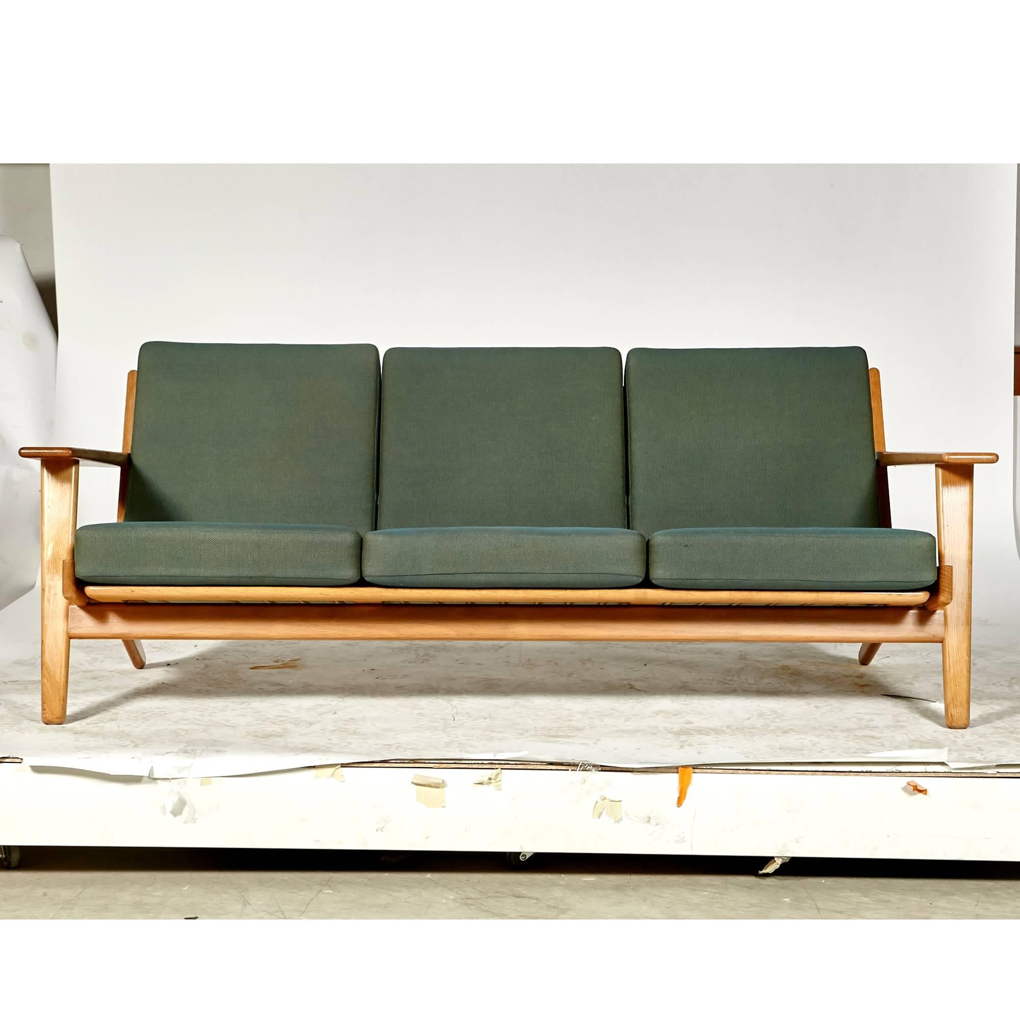 Vintage 1960s Hans J. Wegner three seat sofa designed for GETAMA of Denmark in oak Model GE-290. Sofa has paddle arms and original green fabric. Measures: Arm height 20.5