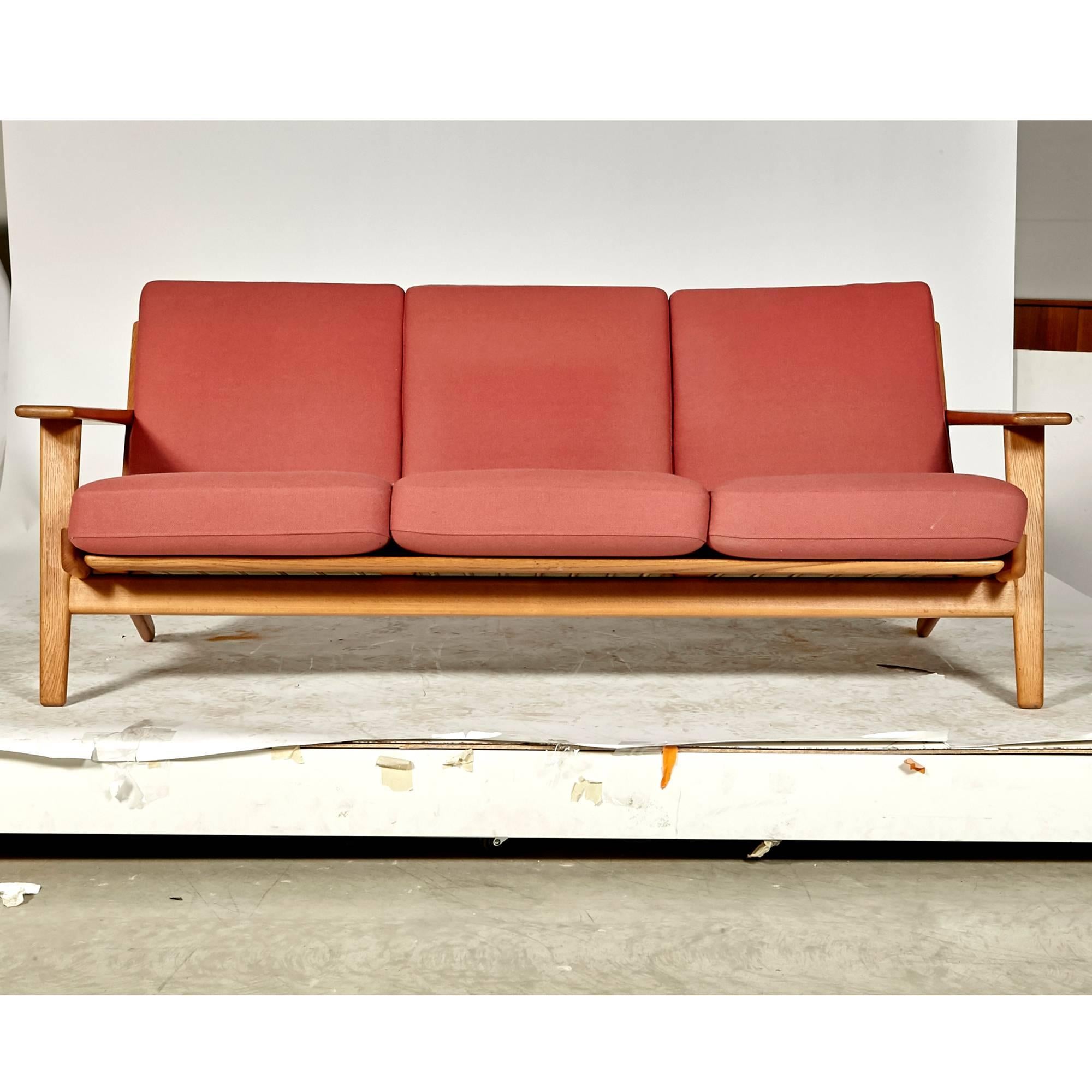 Vintage 1960s Hans J. Wegner three seat sofa designed for GETAMA of Denmark in oak Model GE-290. Sofa has paddle arms and original light red fabric. Arm height: 20.5