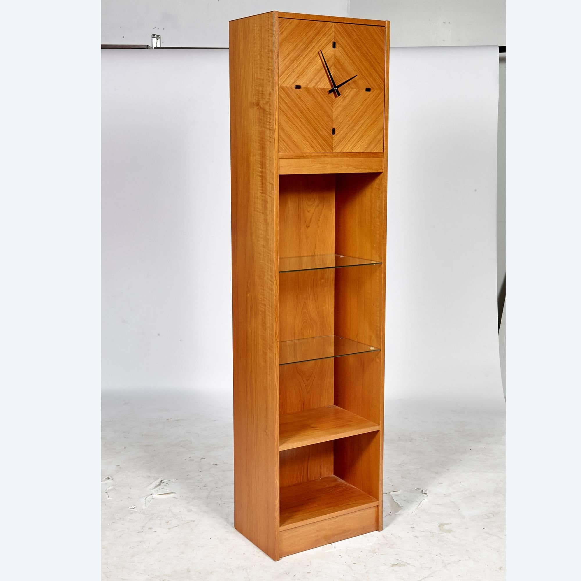 Vintage Scandinavian Modern tall Danish teak grandfather clock with built-in curio shelves. The clock is battery operated and in working condition. The shelves are a mix of glass and wood and face is a diamond inlaid style pattern.