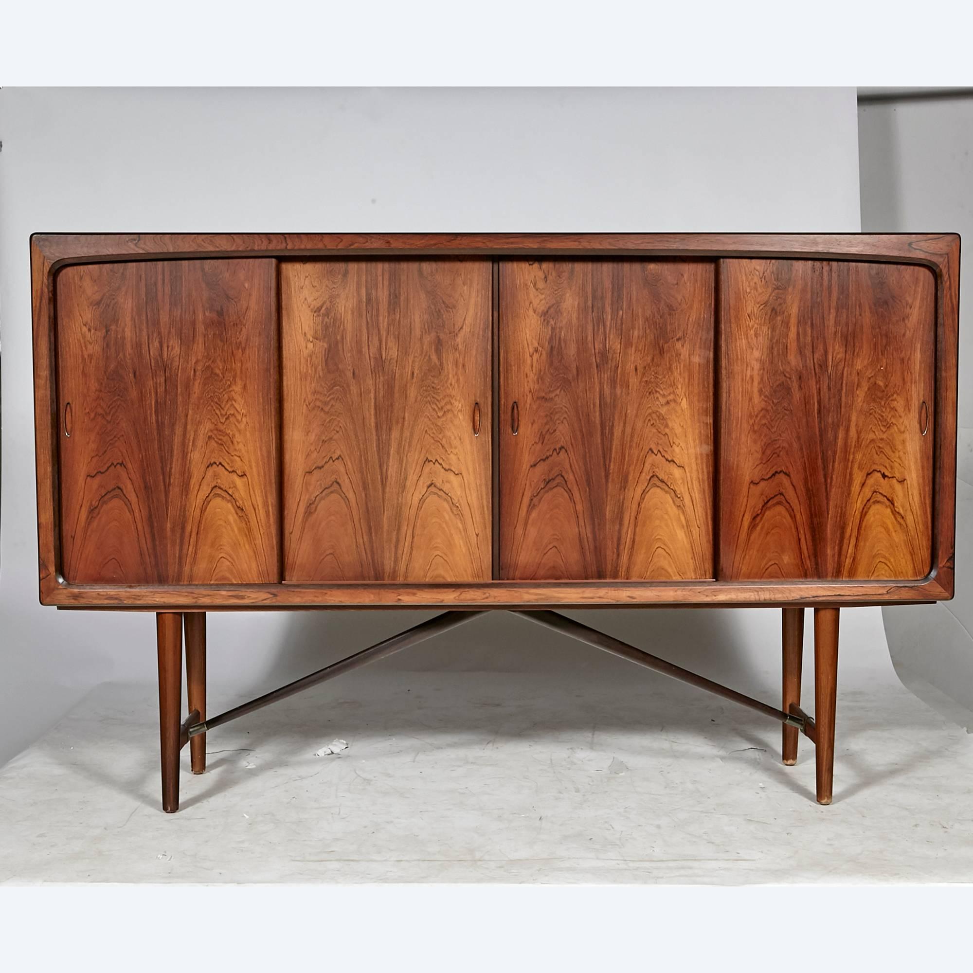 Vintage Scandinavian Modern Danish rosewood sideboard by A. L. Johansen & Søn in Kolding Denmark, circa 1960s. Interior has adjustable shelves, flat drawers for storage and a small mirrored back dry bar area. Base has a cross stretcher for support.