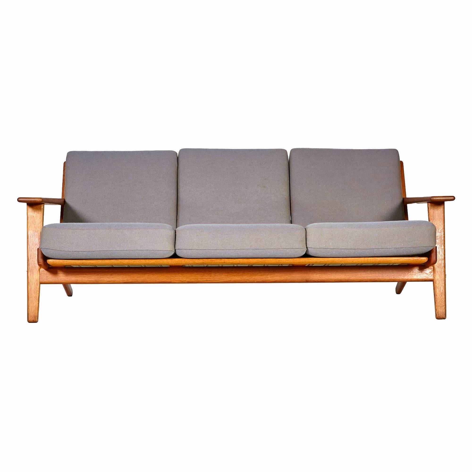 1955 three seat oak GE 290 sofa with paddle arms designed by Hans J. Wegner for GETAMA of Denmark. Original fabric with minor wear from use. Marked on the underside.