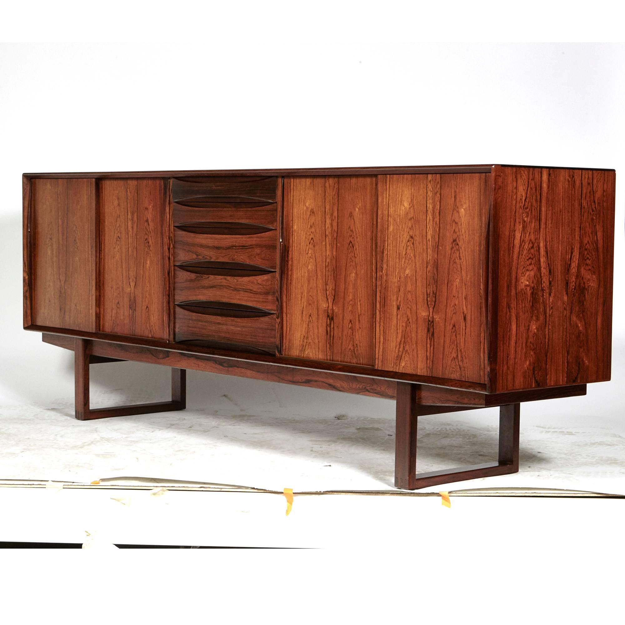 Vintage Danish rosewood credenza or sideboard with sled legs designed by Arne Vodder in the 1960s. The credenza has five drawers and adjustable shelving for storage. Sculpted wood drawer pulls. All-over nice rosewood grain. Excellent condition.