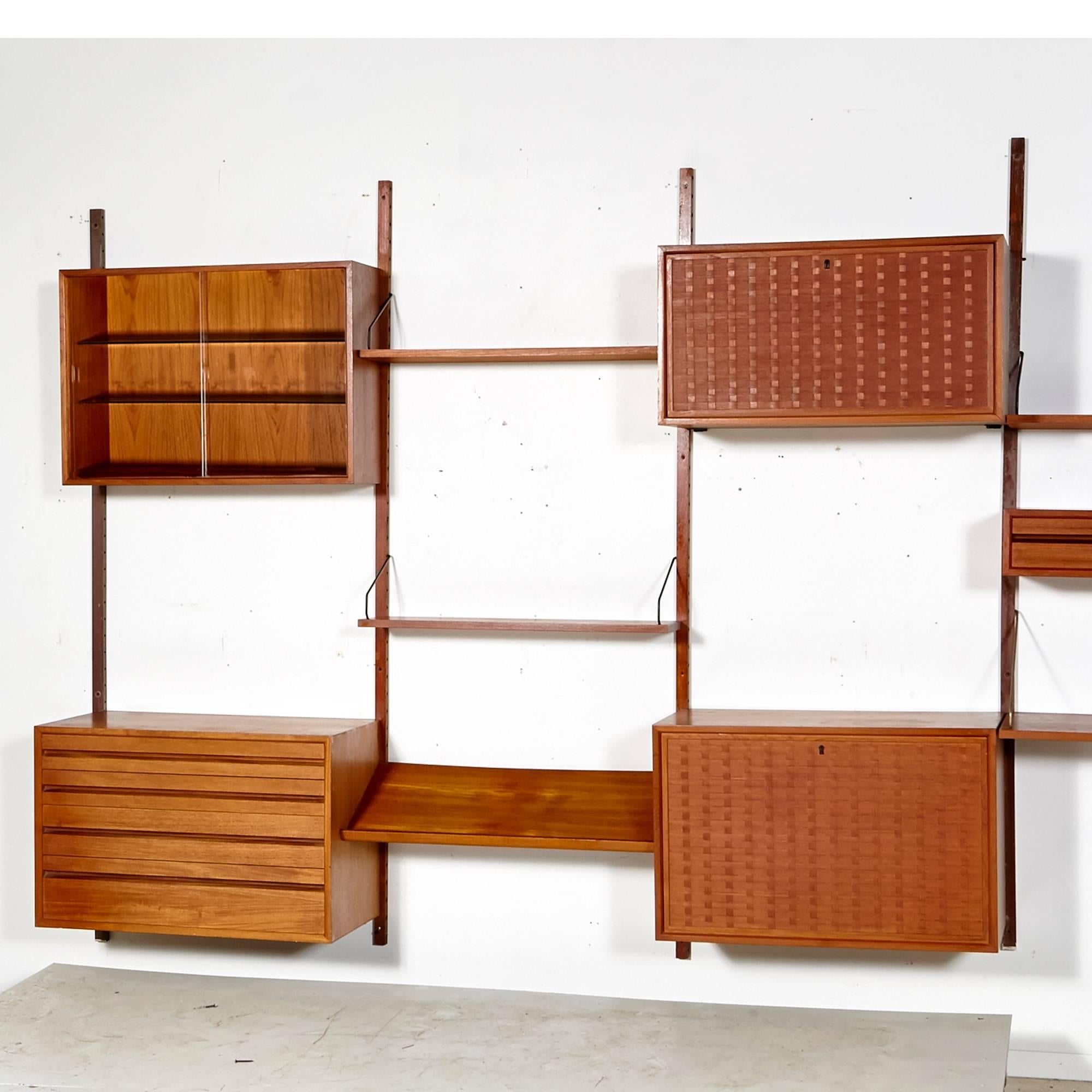 Vintage seven bay teak modular wall unit designed by Poul Cadovius for Cado of Denmark, 1970s. This impressive seven bay wall unit can be configured any way desired. It has shelving, sliding glass or teak front storage and drawer/desk units.