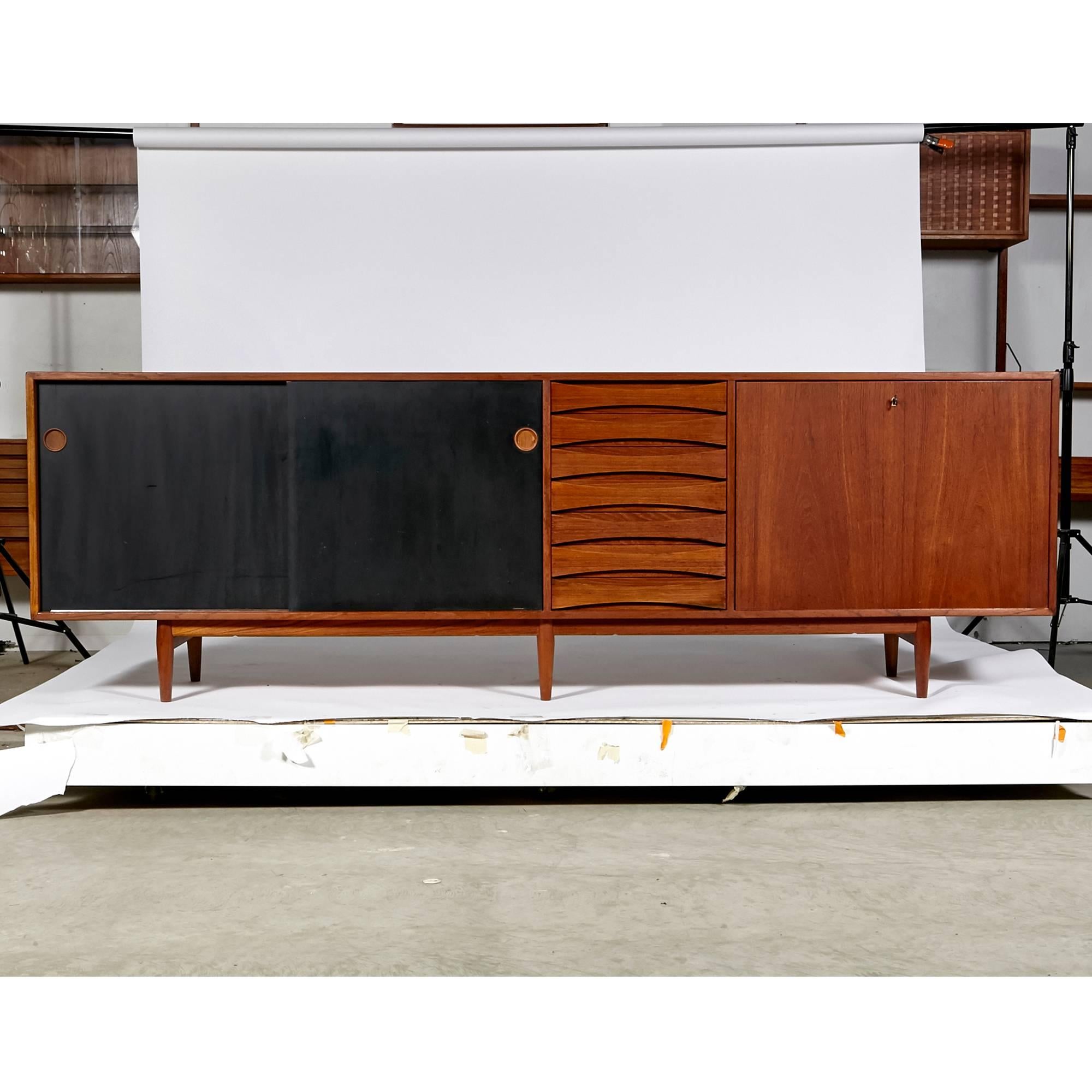 Vintage Arne Vodder teak sideboard model 29a with black reversible doors for Sibast Mobler, Denmark, 1959. This well constructed teak credenza has reversible sliding doors (can be teak or black), drawers for storage and a flip down cabinet with