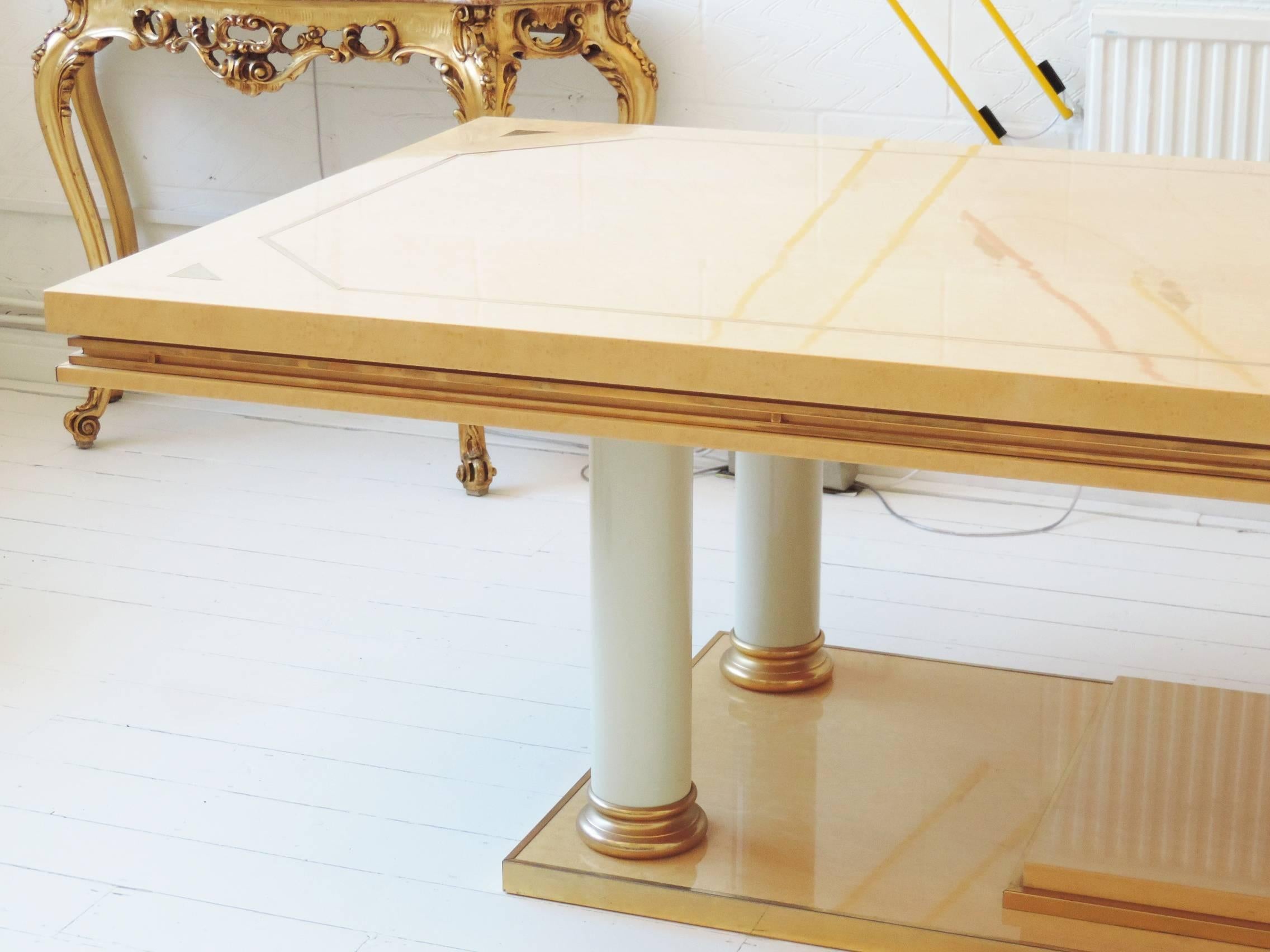 Stunning late 20th century table by luxury Italian brand Turri.

Lacquered bird's-eye maple with brass banding; inlaid to center with a brass diamond and triangles to corners, enamelled ivory columns with gold-plated ends and brass edging to