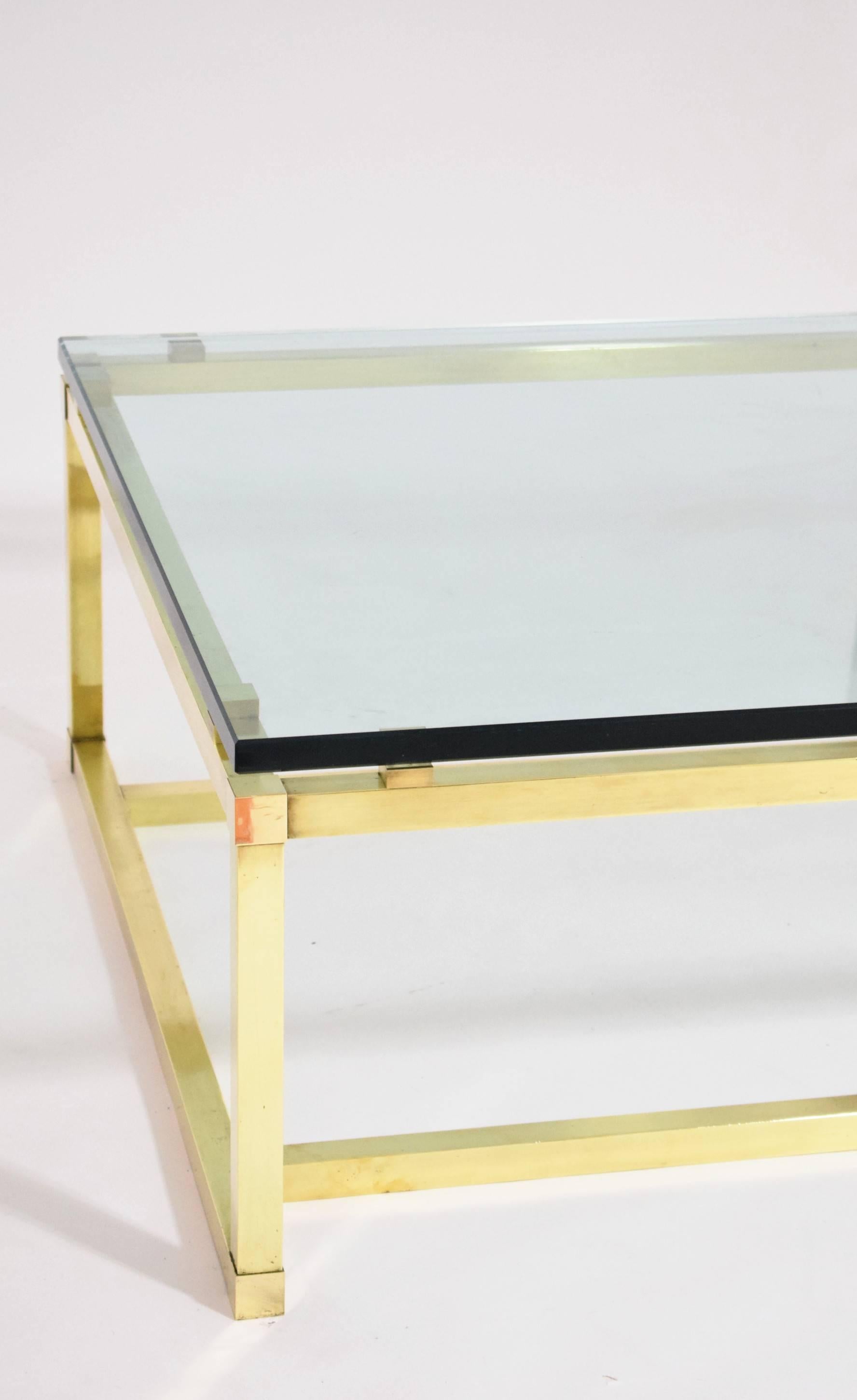 A large and gorgeous 1970s coffee table made from brass with a beautiful thick glass top.
   