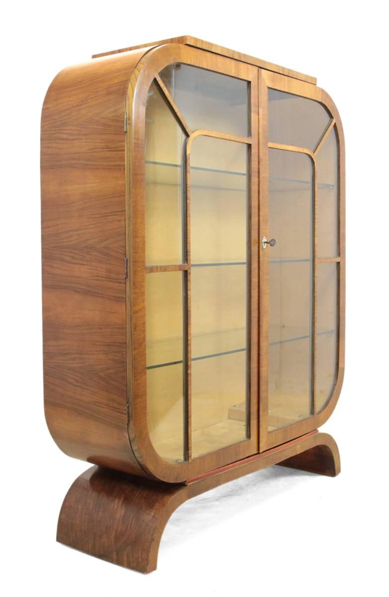 Art Deco walnut display cabinet, circa 1930.
A figured walnut, astragal, glazed display cabinet from the Art Deco period in the 1930s, with two doors opening to reveal three glass shelves. Having its original key and silver fan escutcheon. This
