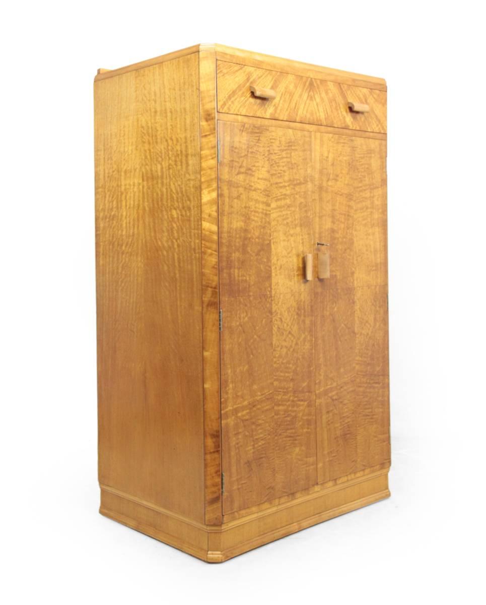 English, Art Deco tall boy, circa 1930.
An English produced Art Deco tallboy cupboard, with drawer above in light satin birch veneer. Behind the doors are three Mahogany slide type drawers. This cabinet is in excellent condition throughout and has