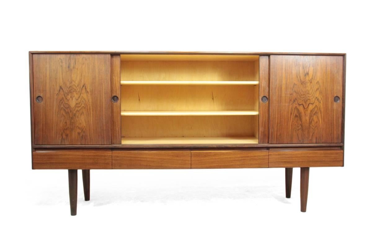 Mid-Century Danish rosewood sideboard, circa 1960.
A four-door rosewood sideboard with drawers below, shelves and drawers behind sliding doors with sunken in handles. East Indian Rosewood exterior with chestnut lined interior with adjustable