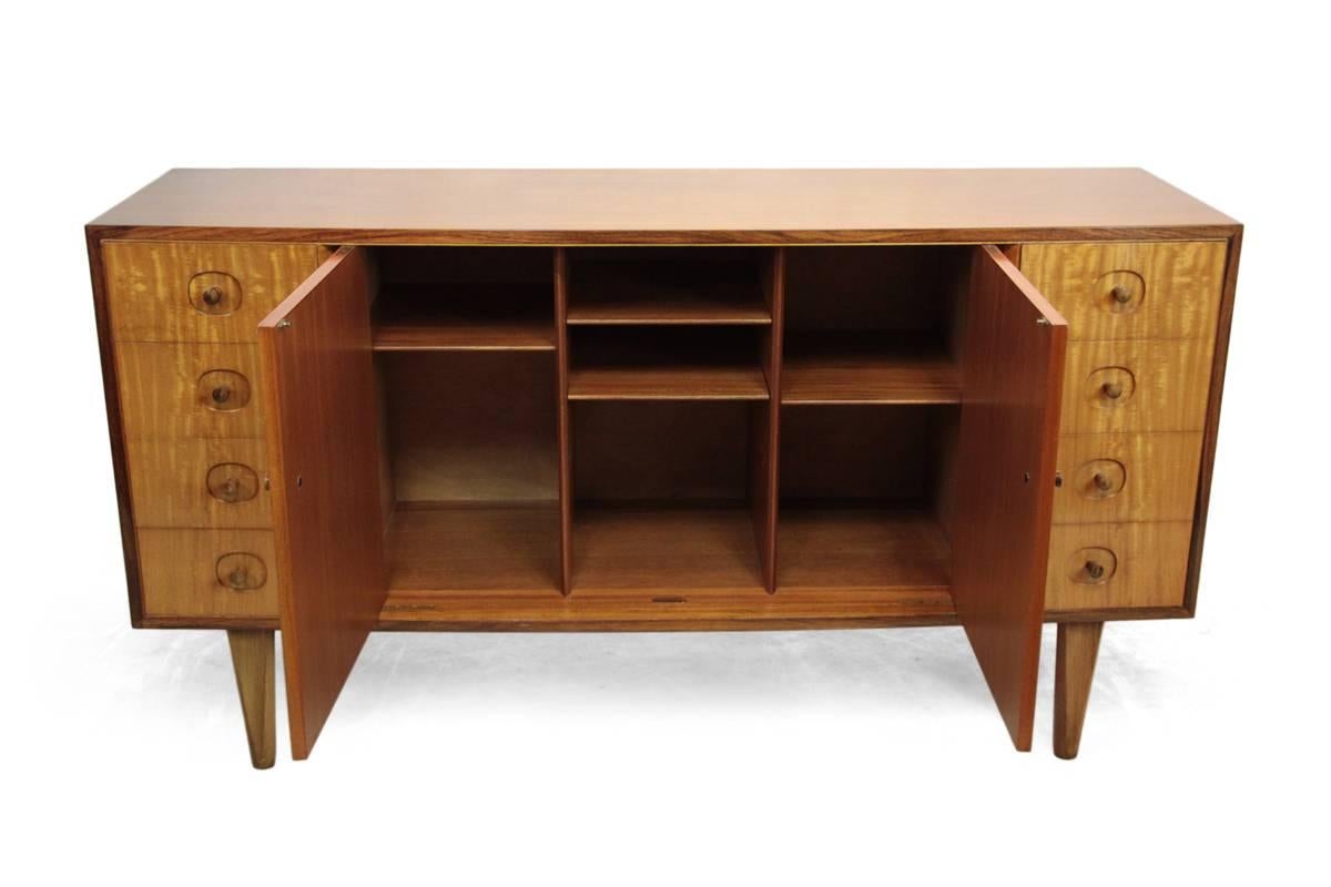 Mid-Century sideboard by Gordon Russell.
An excellent quality sideboard, designed and produced by Gordon Russell in the early 1960s having satin wood front and rosewood top and sides, this sideboard has a solid mahogany carcuss with hand cut