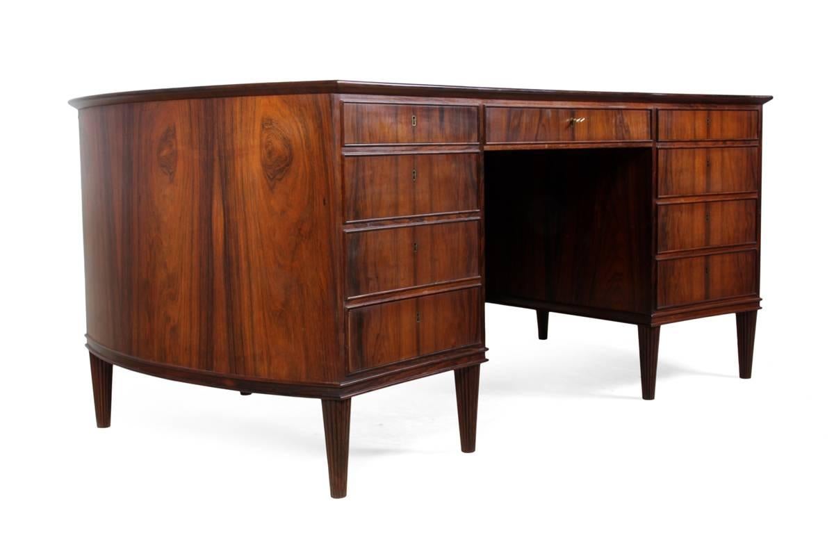 Danish rosewood desk, circa 1950.
A nine drawer, large, one-piece pedistal desk with kidney shaped top, standing on fluted legs. With early Mid-Century Modern Classic style, almost on the turn between Mid-Century Modern from Art Deco. A good solid